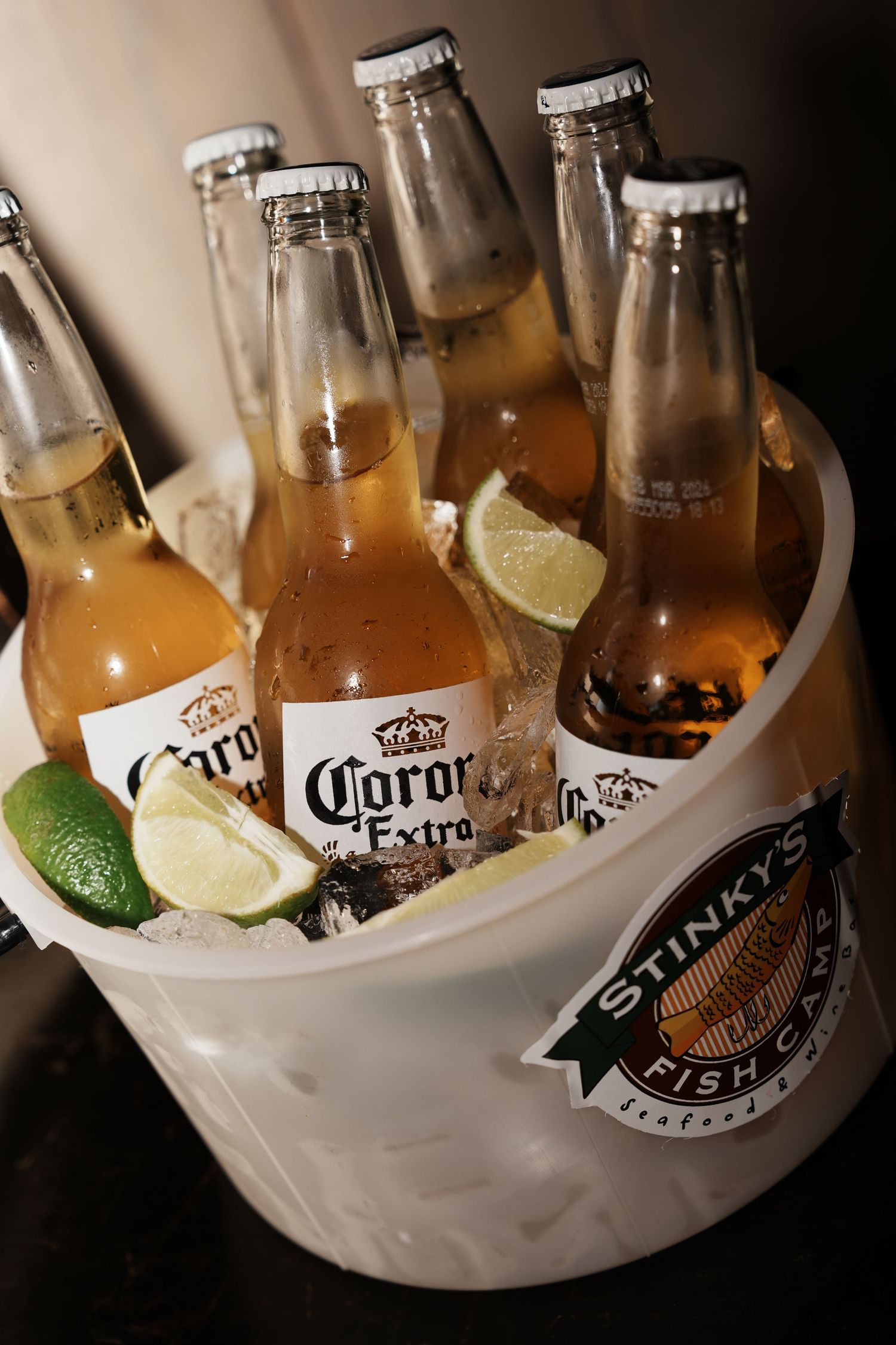 Corona Extra beer bottles chilling in an ice bucket with fresh lime wedges and a Guinness logo.