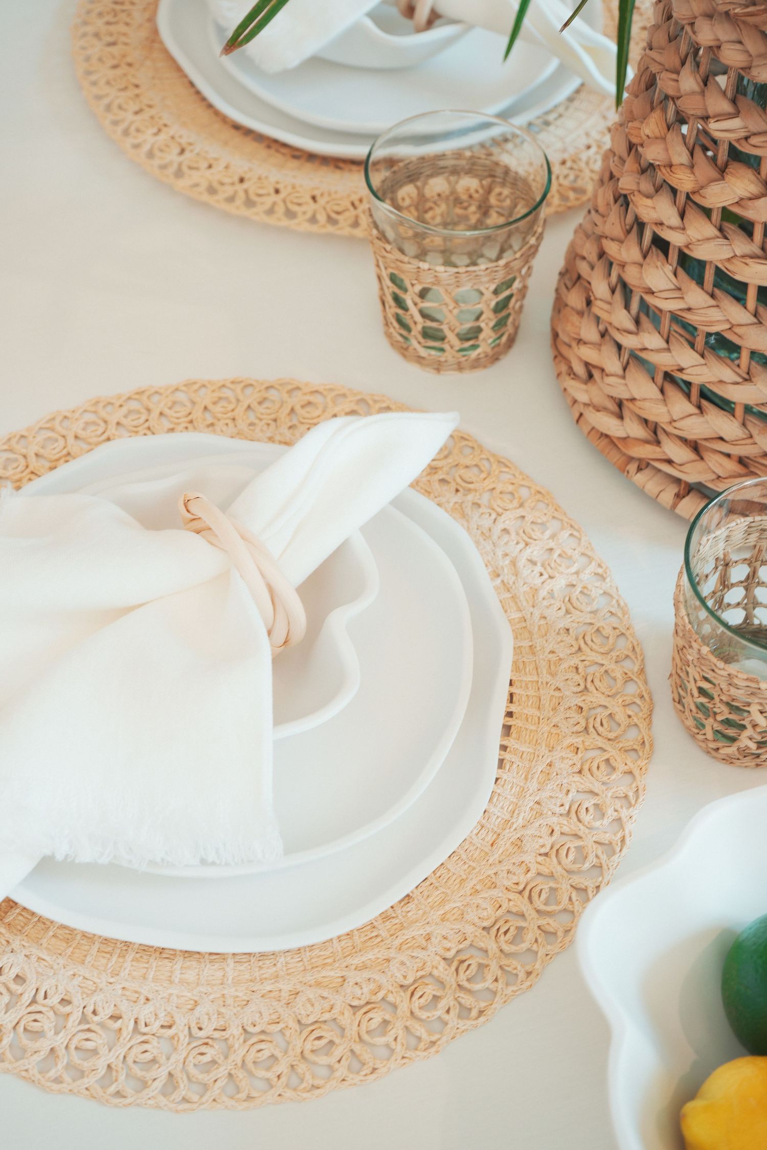 An elegant table setting with white plates on golden decorative chargers and intricate glassware against a neutral background.