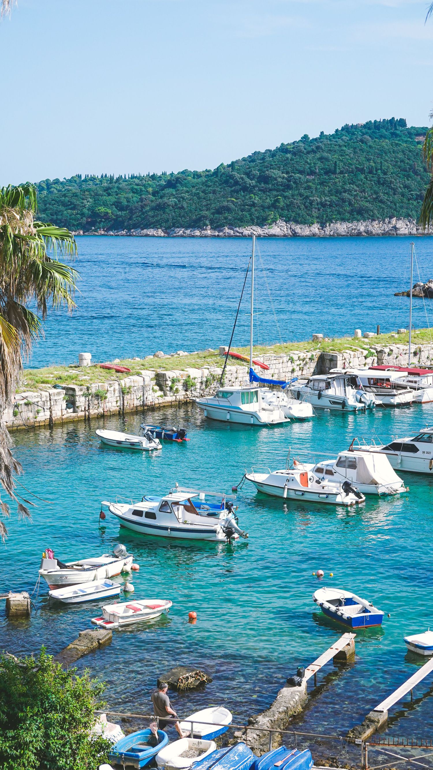 Mediterranean marina with boats anchored in crystal clear turquoise waters near rocky coastline. croatia coastline print