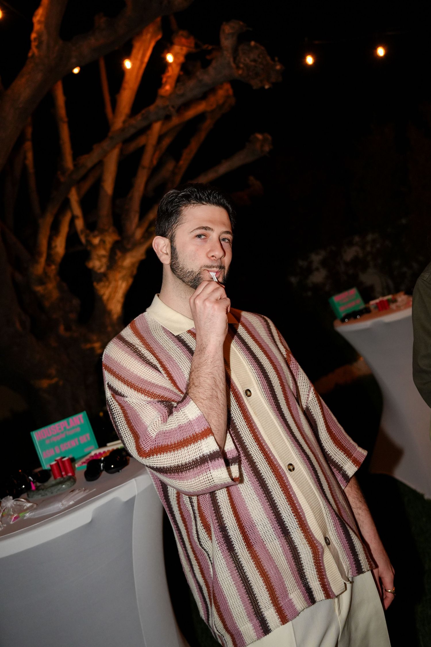 Person wearing a striped poncho-style sweater in brown and cream tones at a nighttime event.