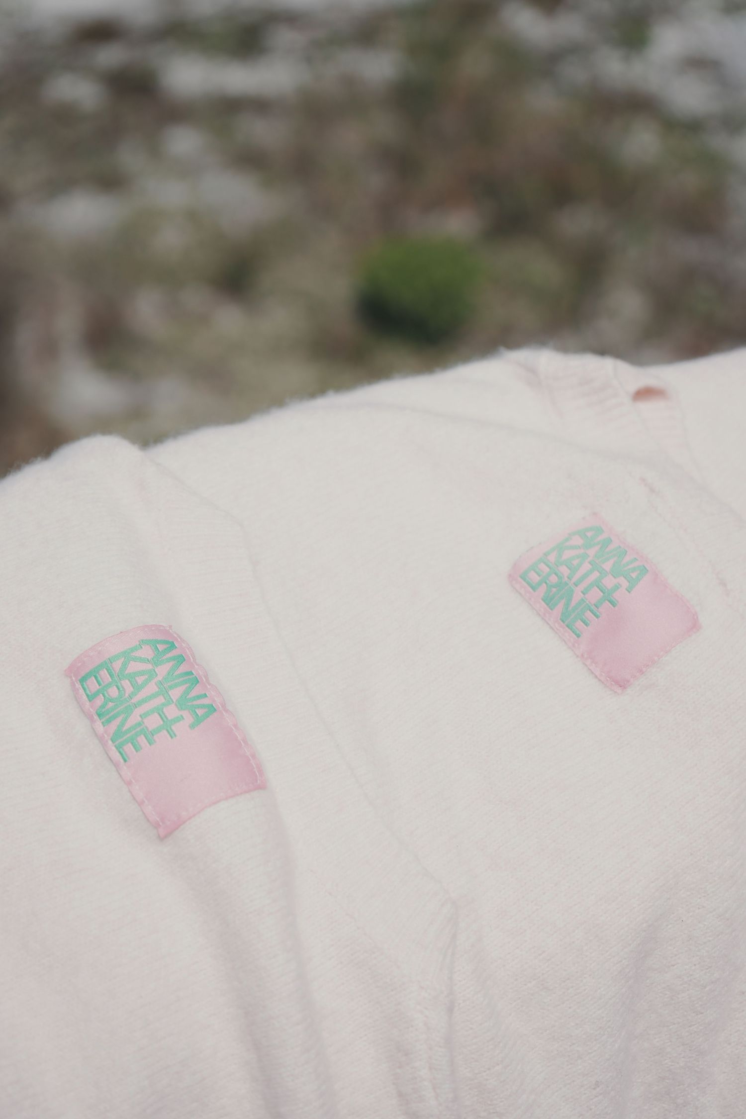 Close-up view of white fabric with pink and turquoise decorative tags or labels attached.