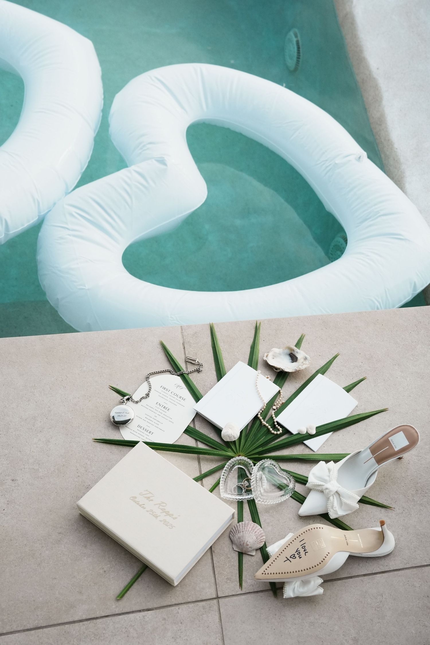 White inflatable balloon decorations with minimalist wedding accessories on a light gray surface.