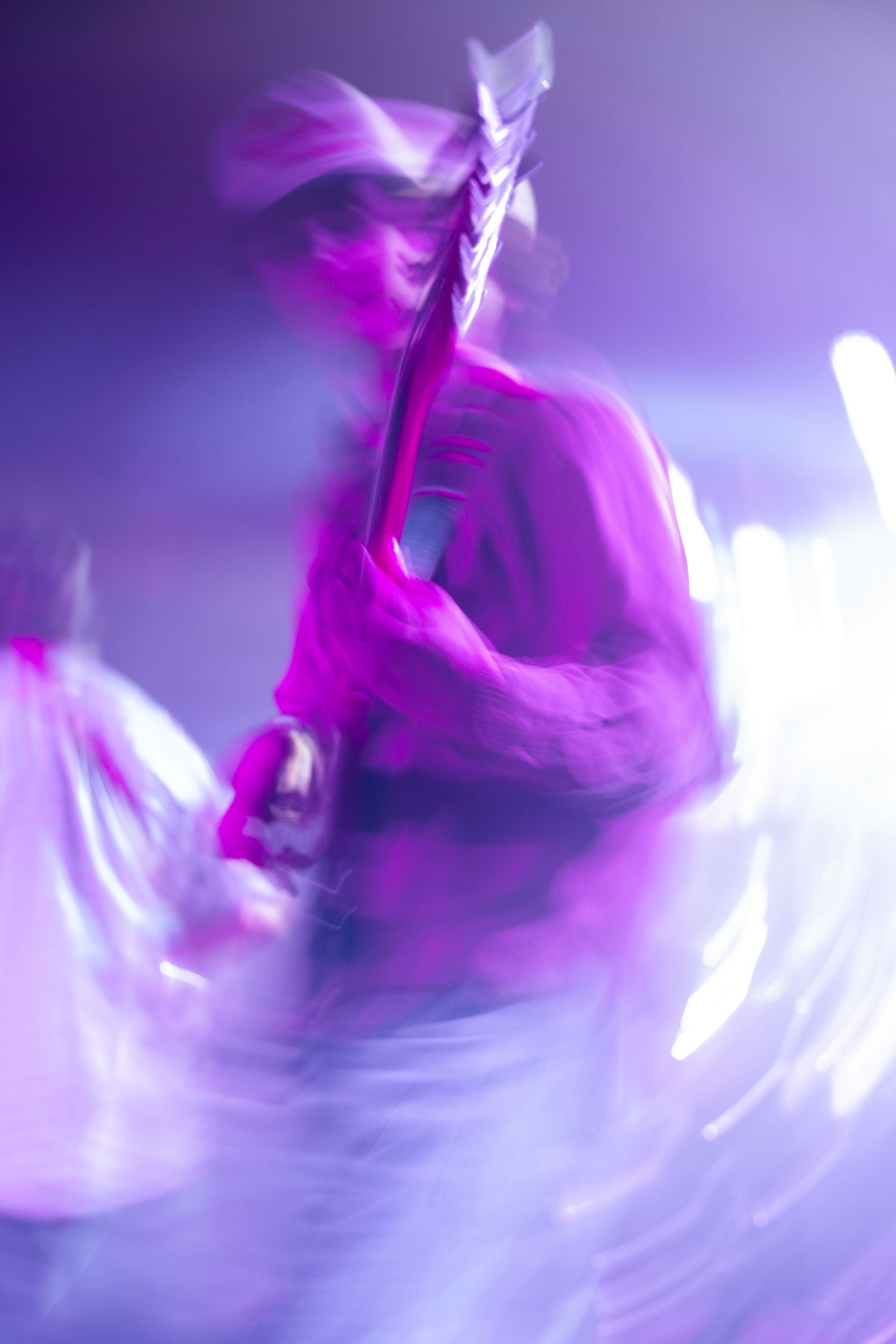 Abstract purple and white motion blur creates a dynamic swirling pattern with ethereal light effects.