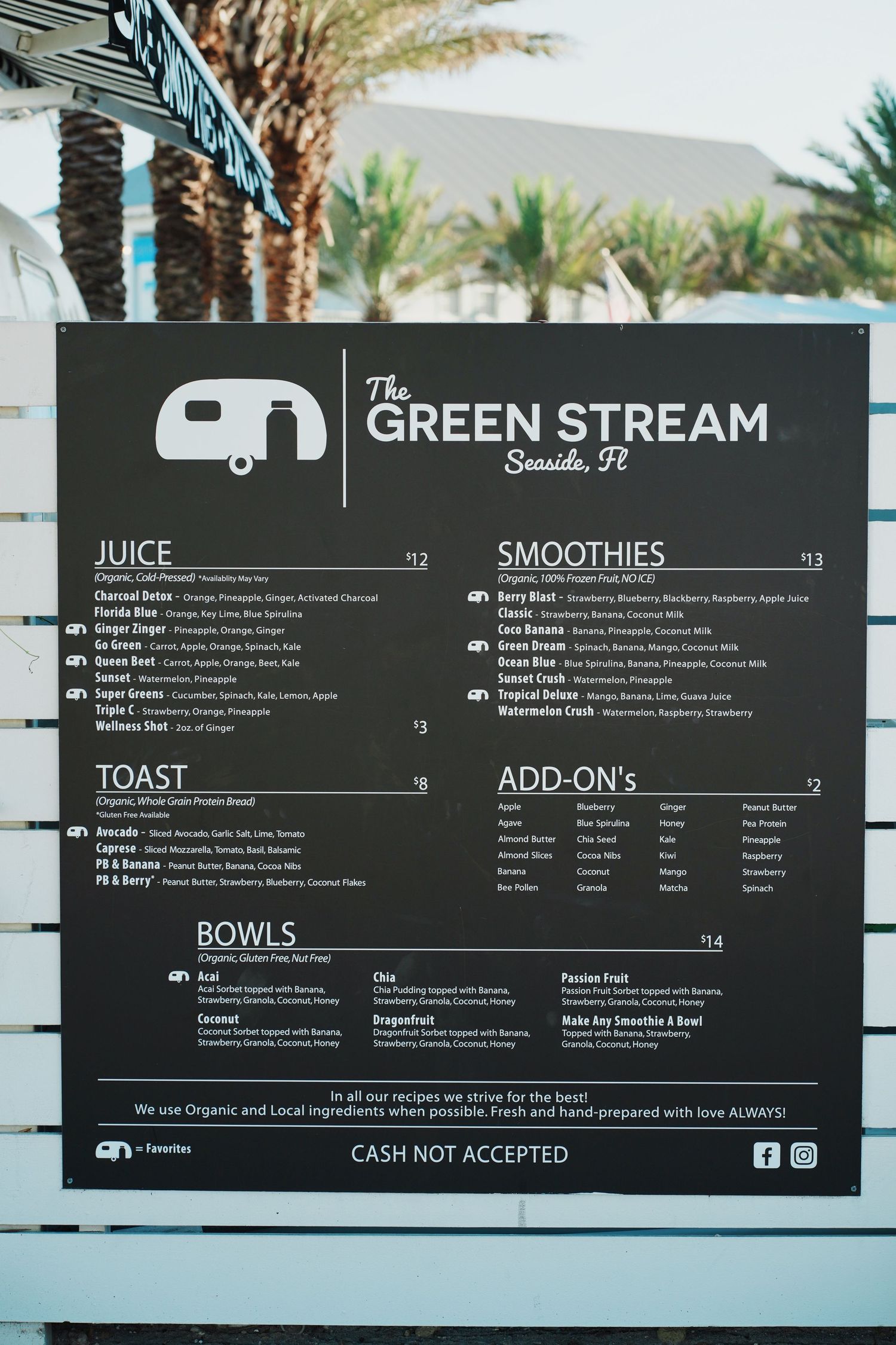 Menu board for The Green Stream juice bar showing prices for juices, smoothies, toast, bowls and add-on items.