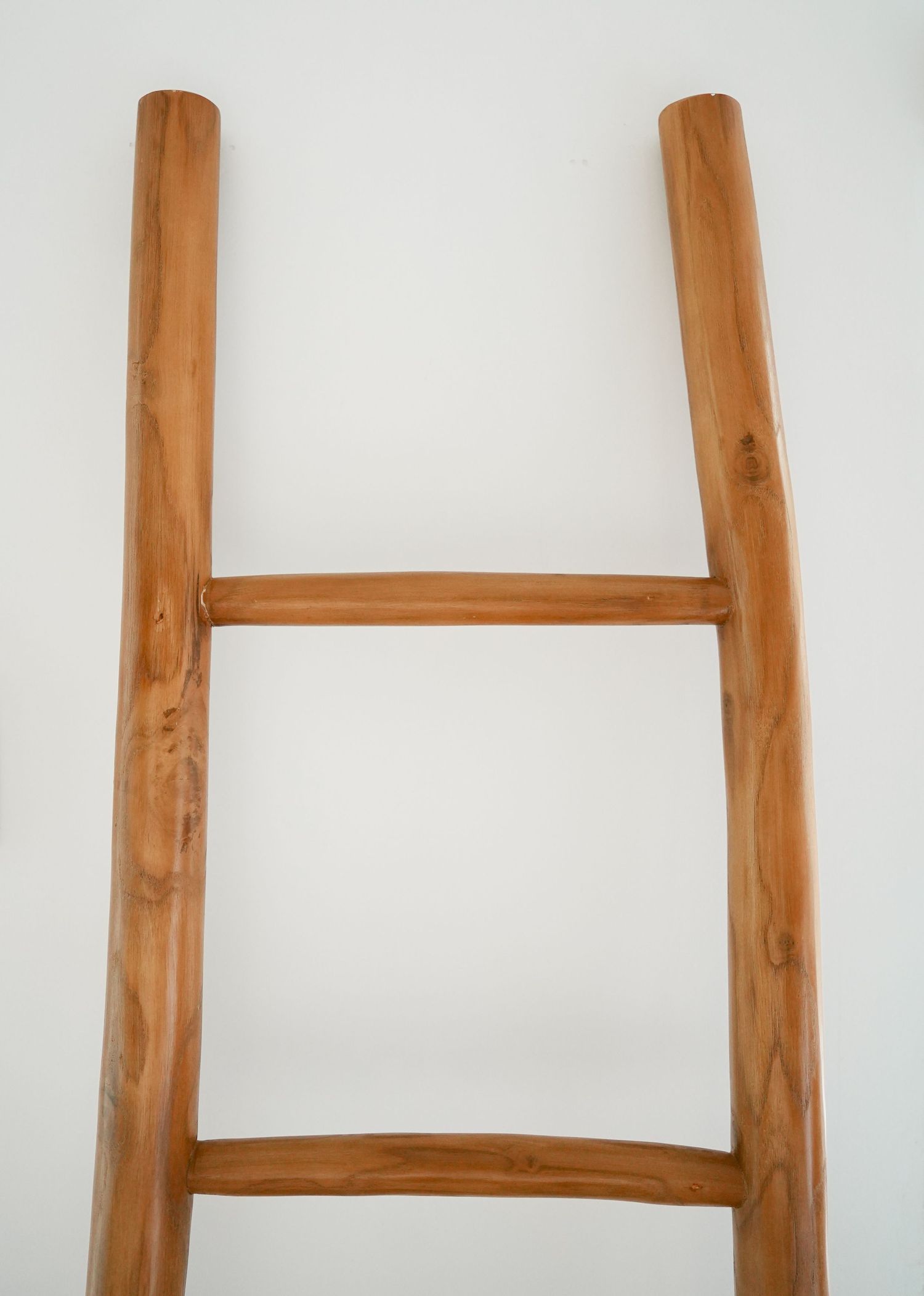Four wooden ladder rungs or horizontal bars mounted on a white wall create a minimalist decorative display.