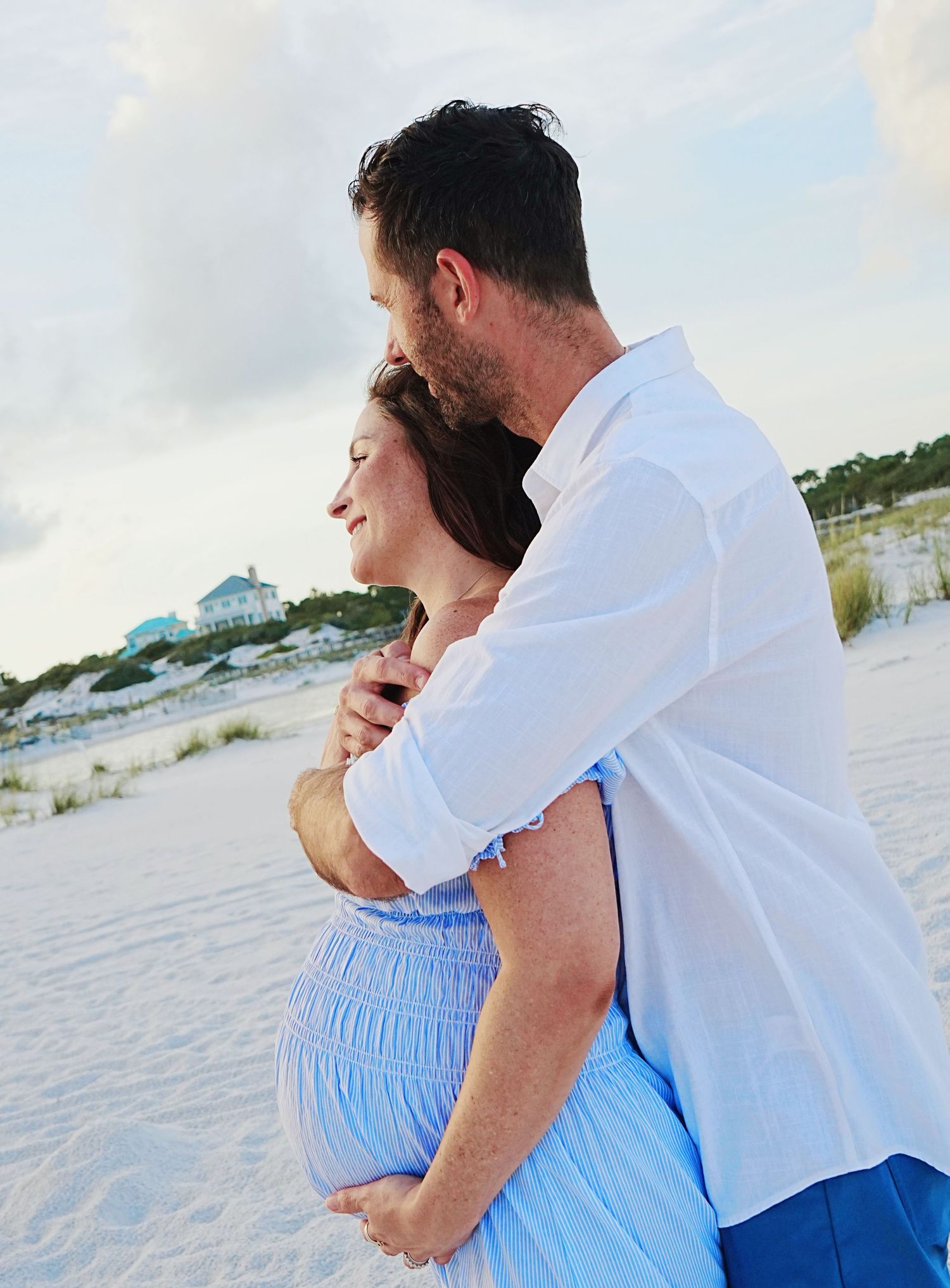 Romantic beach scene with couple in blue and white watching the ocean waves.