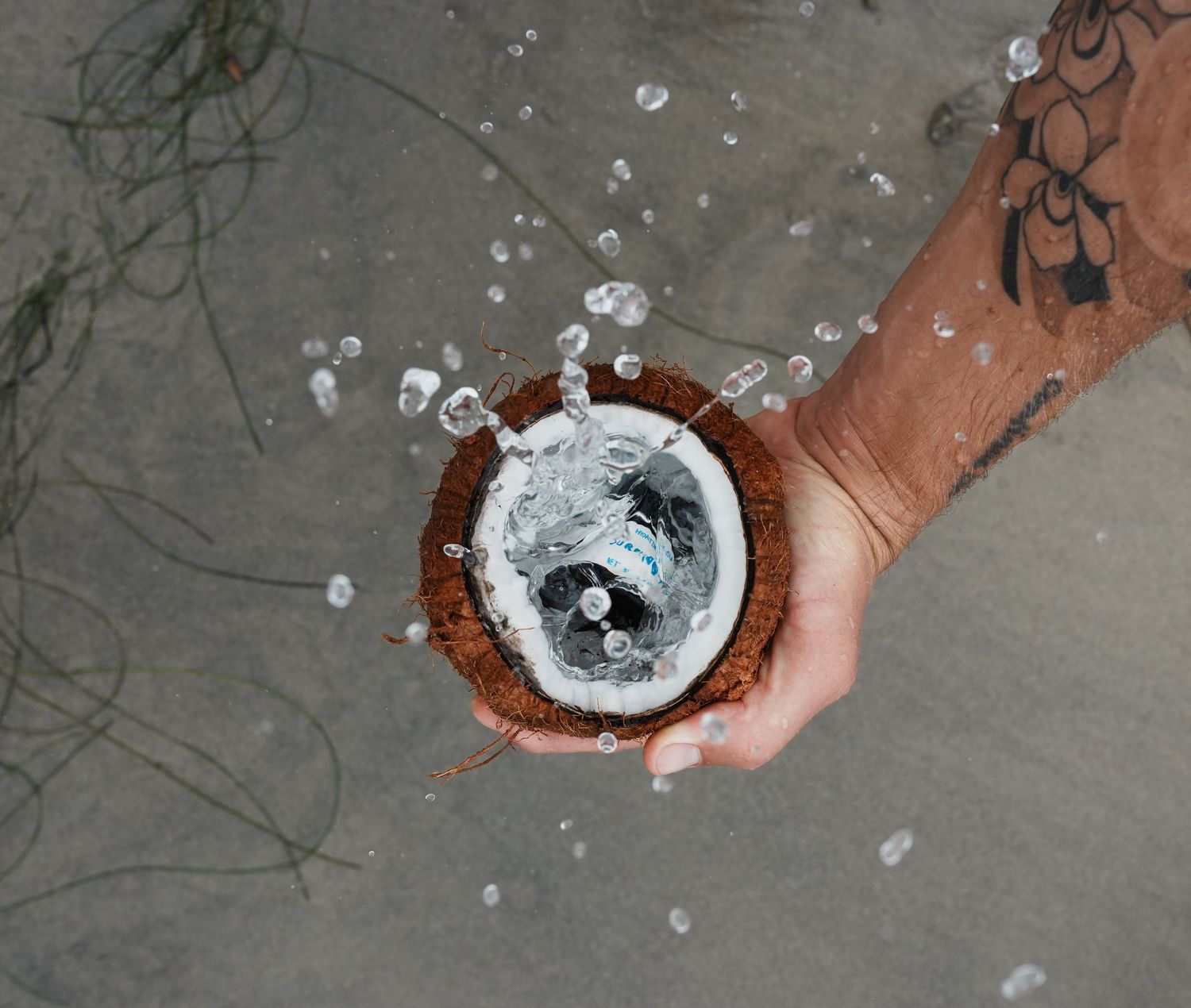 Hands hold a bowl of salt and gradually pour it onto a dark concrete surface creating a scattered pattern.