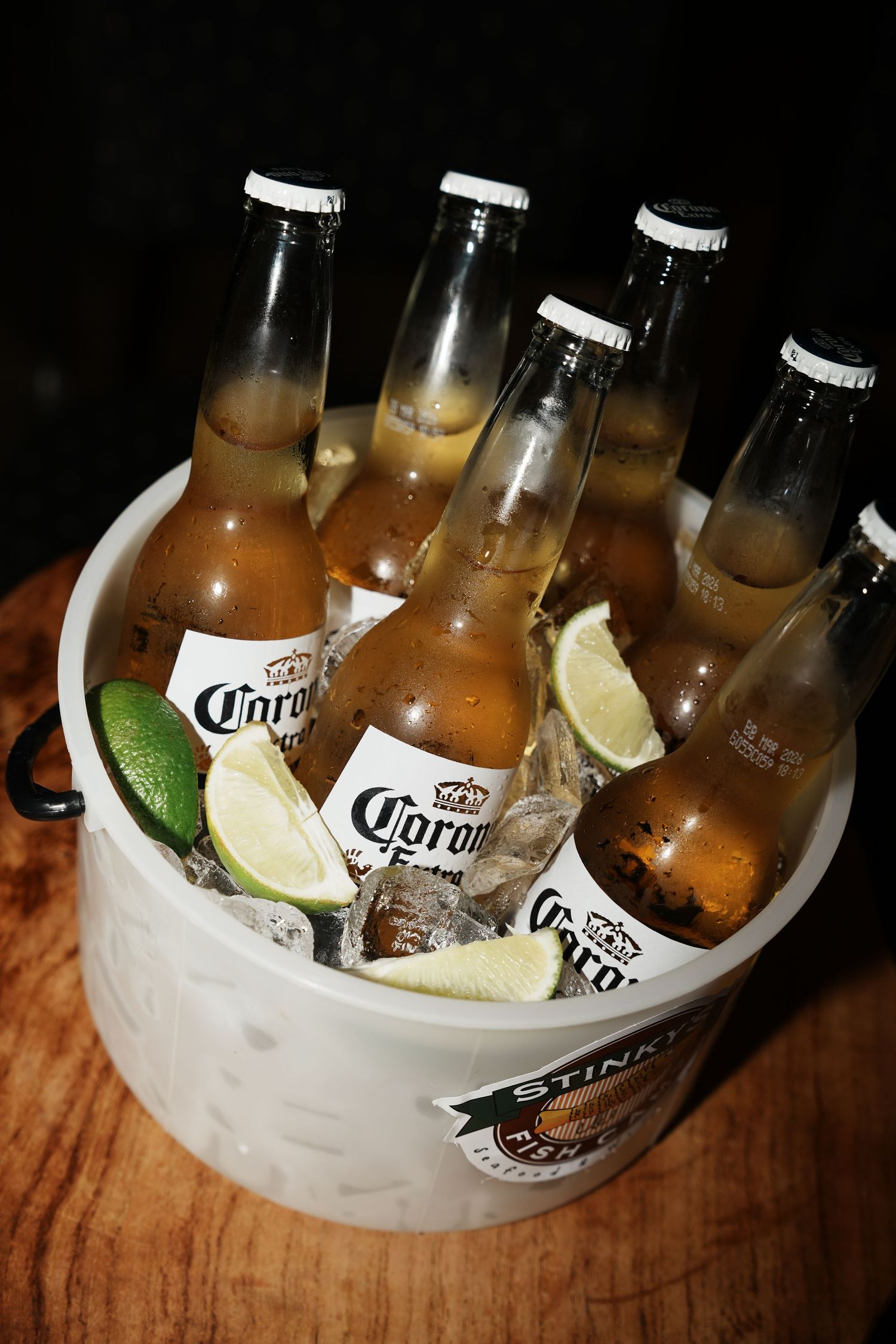 Corona beer bottles chilling in an ice bucket with fresh lime wedges.