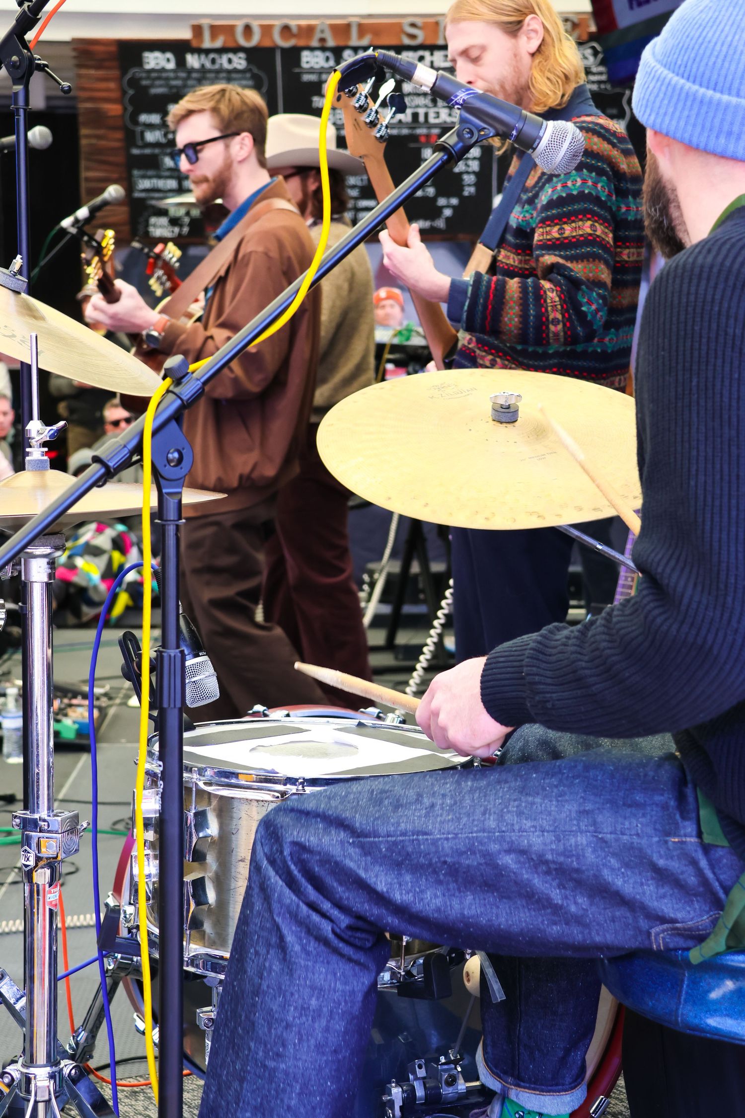 Musicians playing drums and instruments at outdoor festival performance.