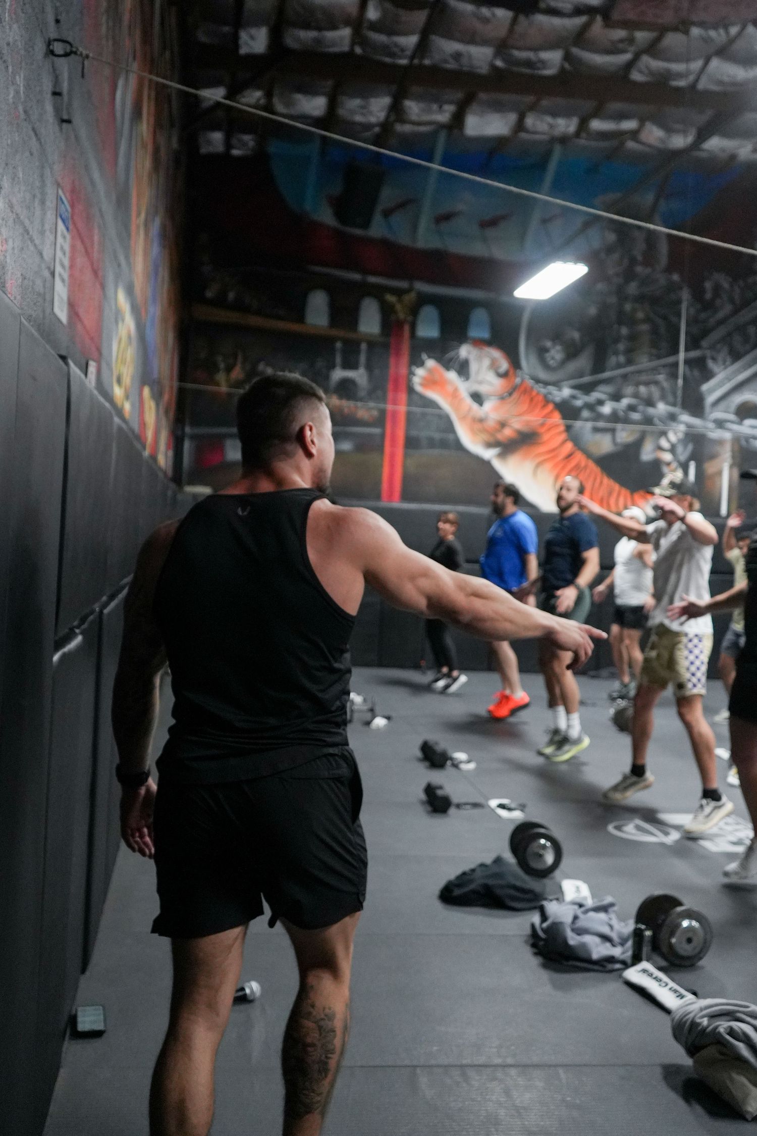 A series of fitness class participants perform dynamic stretching exercises in a dimly lit gym studio.