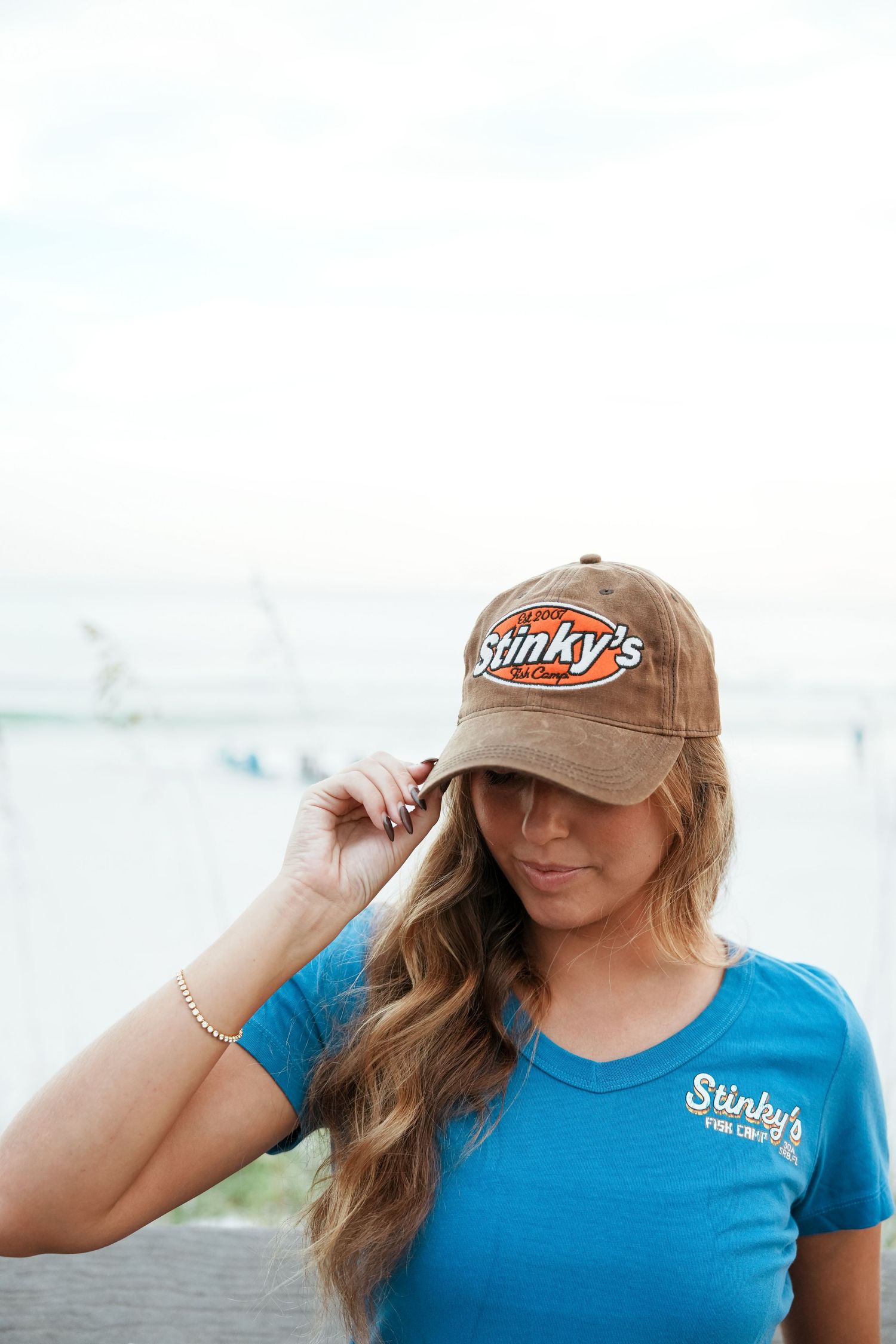 Person wearing a brown Slinky's baseball cap and blue t-shirt poses against blurred background.
