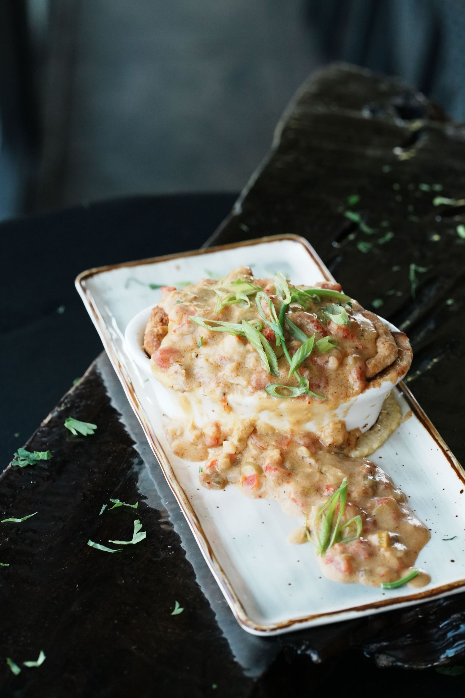 Spicy tuna tartare garnished with fresh herbs served on a small white plate against a dark background.