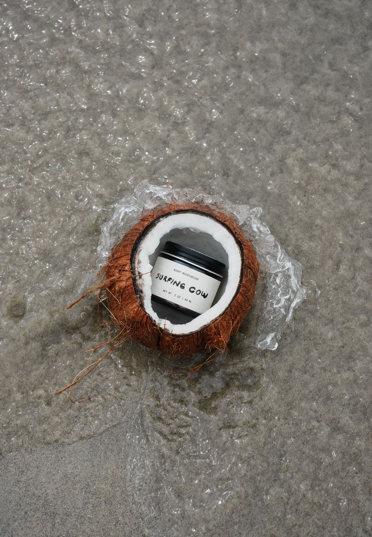 Coconut with surfing brand logo wrapped in plastic on concrete surface.