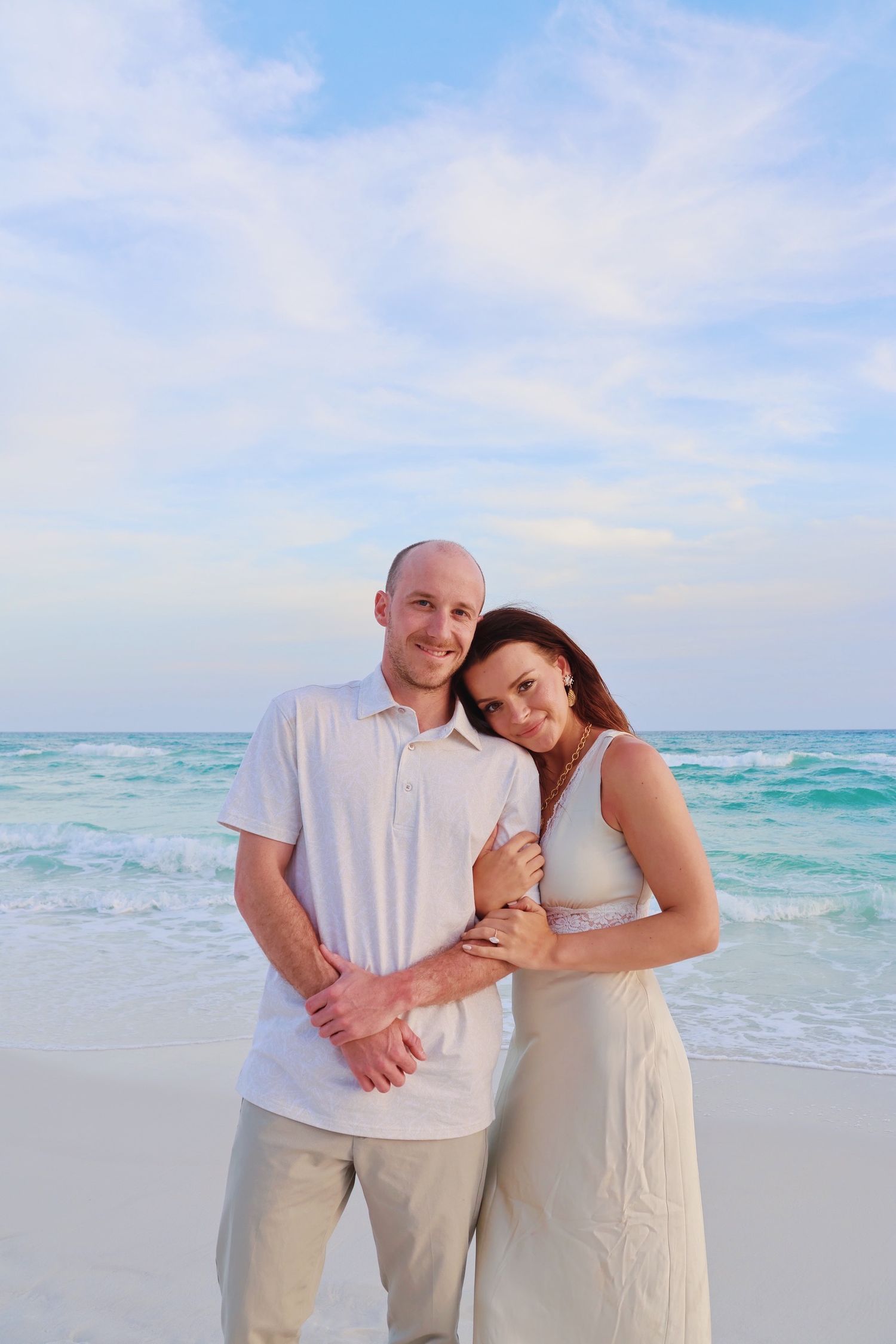 A romantic beach portrait at sunset with turquoise waves rolling in the background.