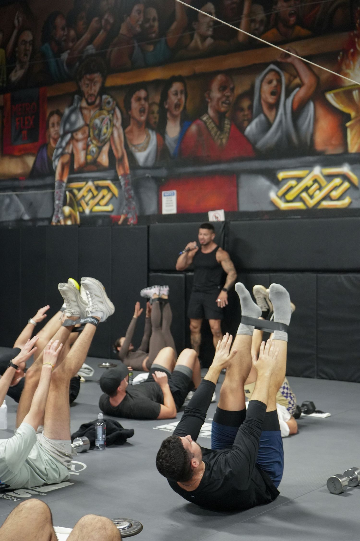 Group of people performing synchronized ab crunches during a fitness class on gray exercise mats.