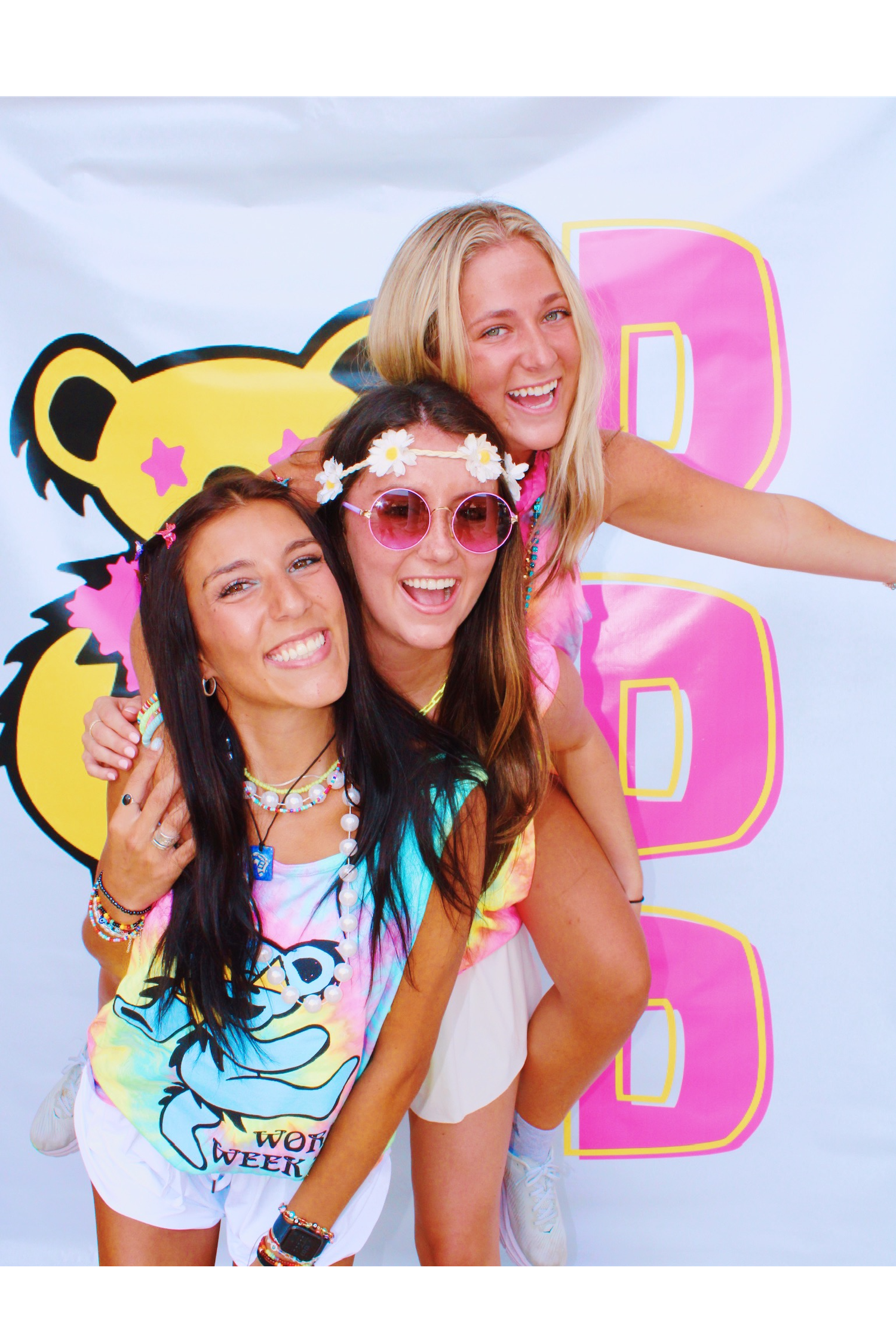 Two friends pose together outdoors on a sunny day making peace signs while wearing casual summer attire.