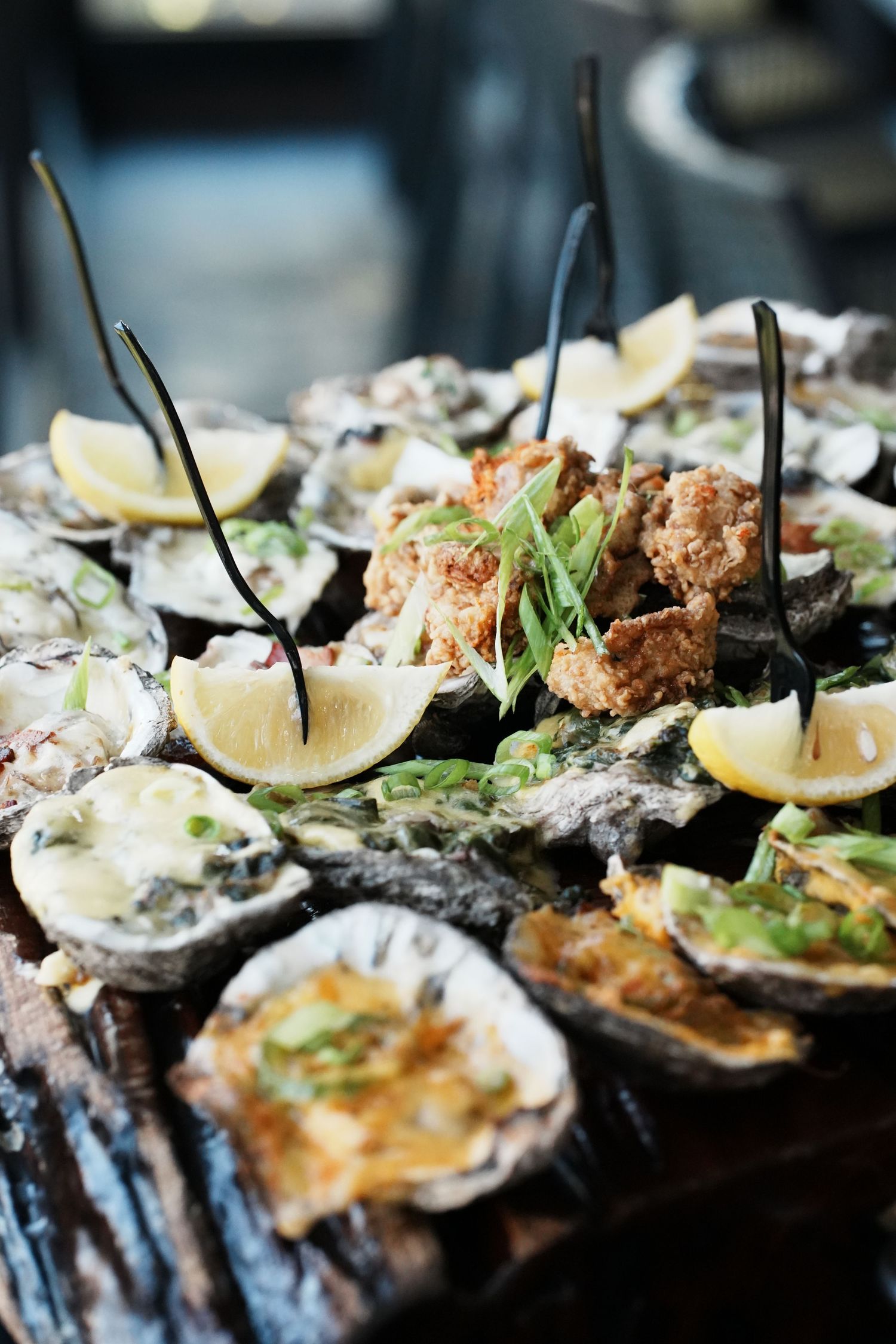 Fresh oysters on the half shell garnished with lemon wedges and microgreens on a dark background.