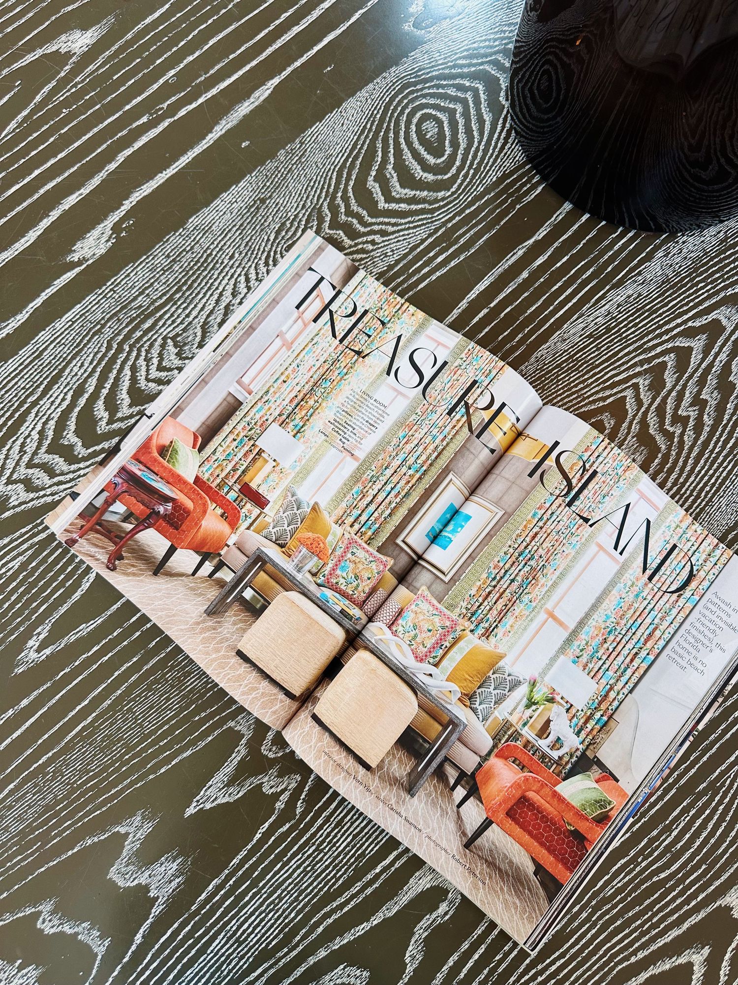 A travel magazine featuring Treasure Island lies open on a textured wooden surface with a dark circular object visible.