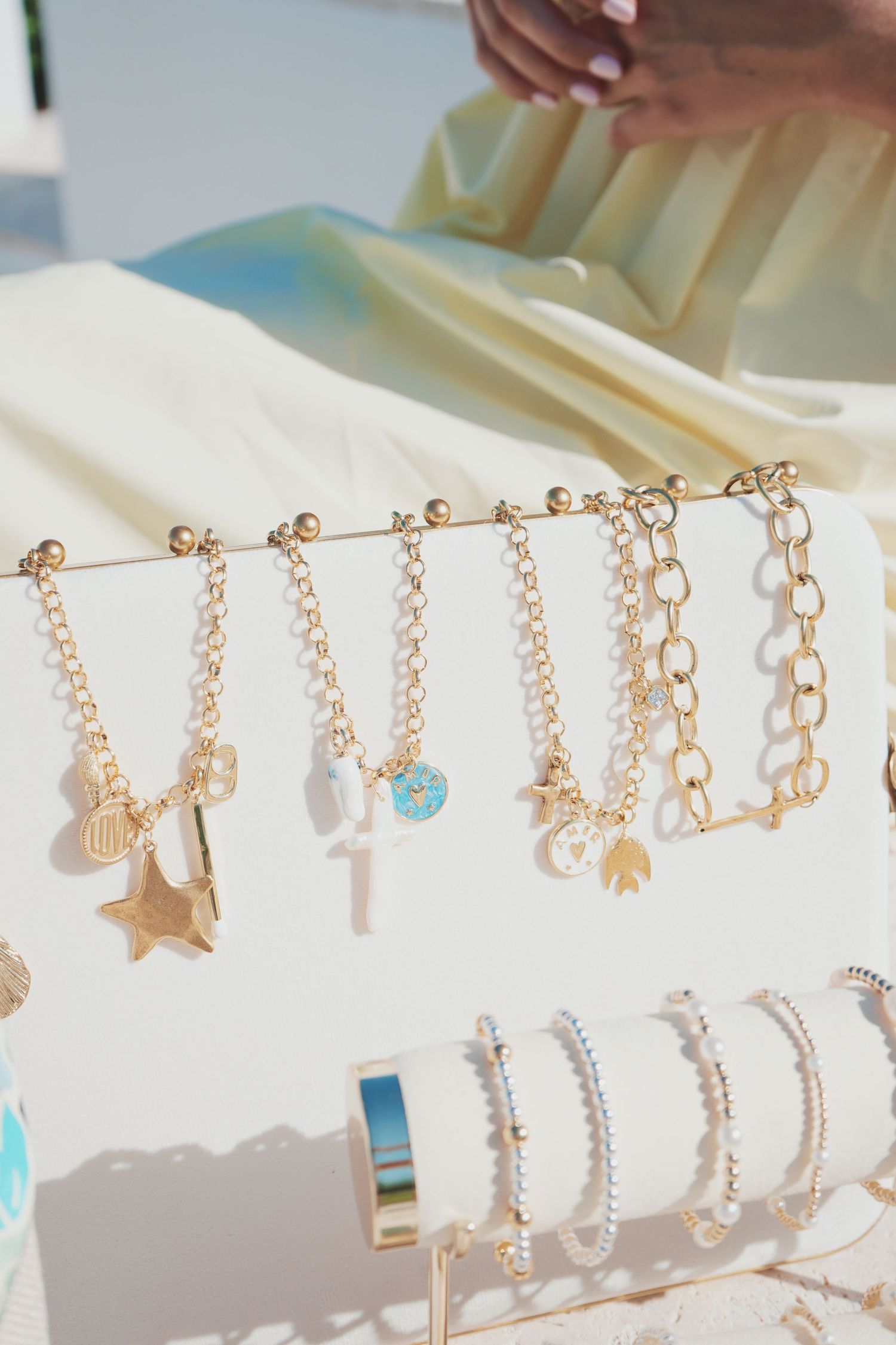 Delicate rose gold charm bracelets with various pendants displayed on a white jewelry stand in a retail setting.