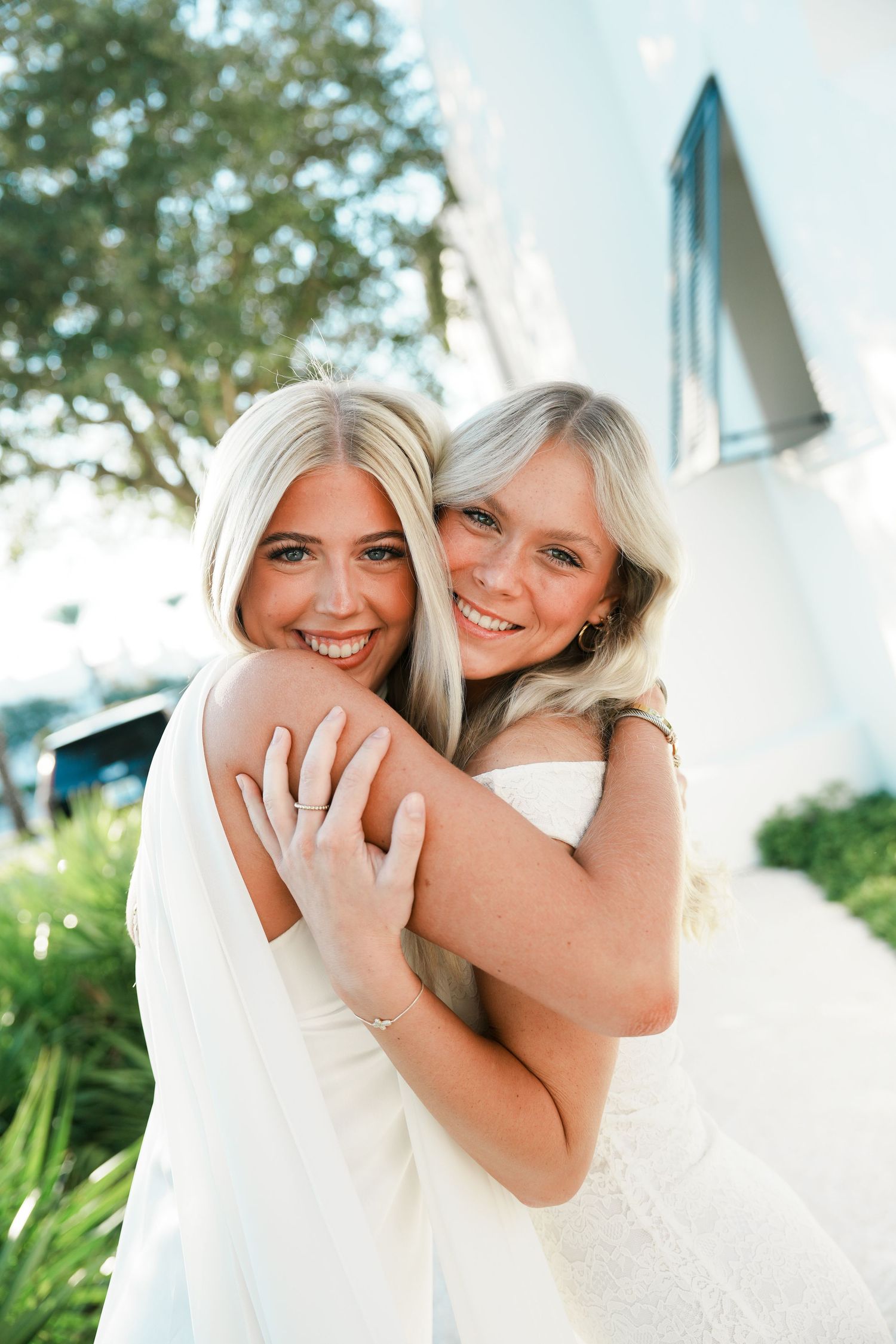 Two people in white outfits share joyful embraces and laughter in a series of candid outdoor portraits.