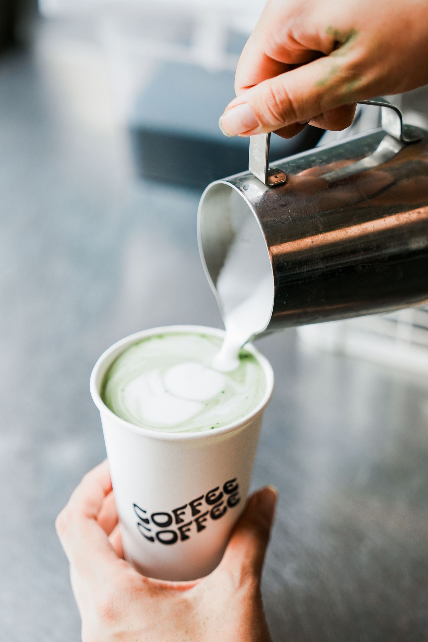 Barista pouring steamed milk into a coffee cup in a sequence of four steps showing latte art technique.