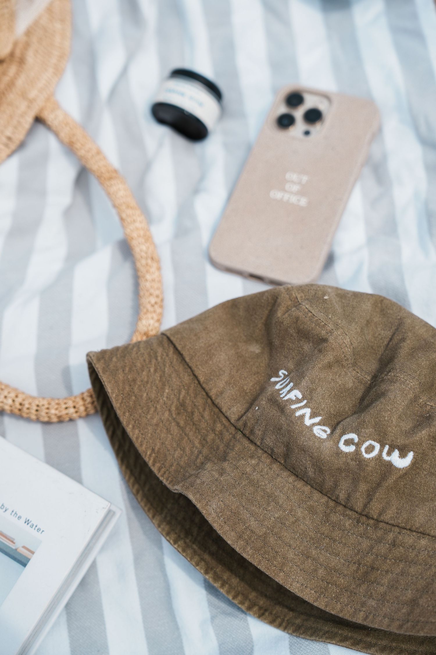 Brown bucket hat with white text displayed on various neutral backgrounds.