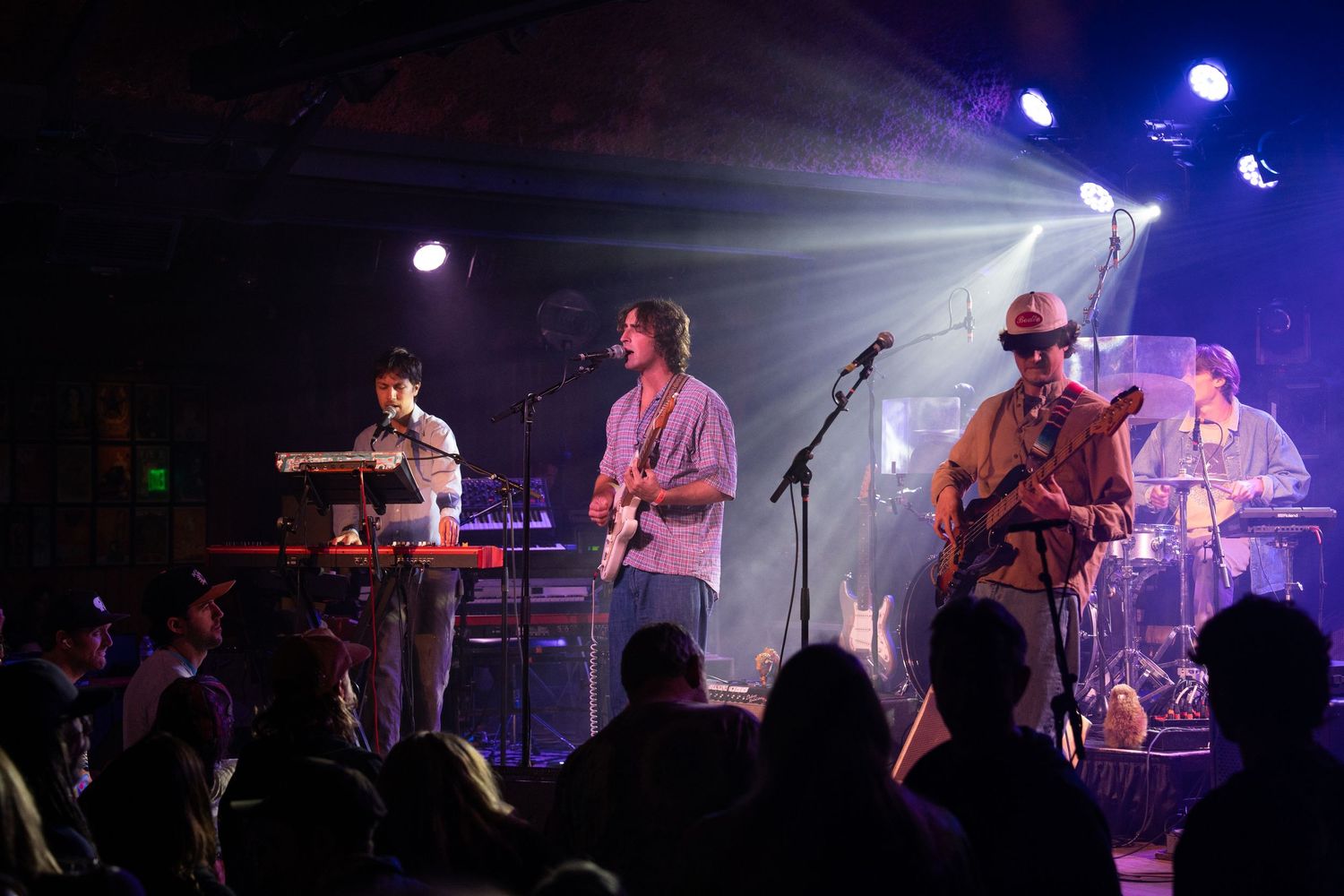 Musicians perform on a dimly lit stage with blue lighting effects during a live concert performance.