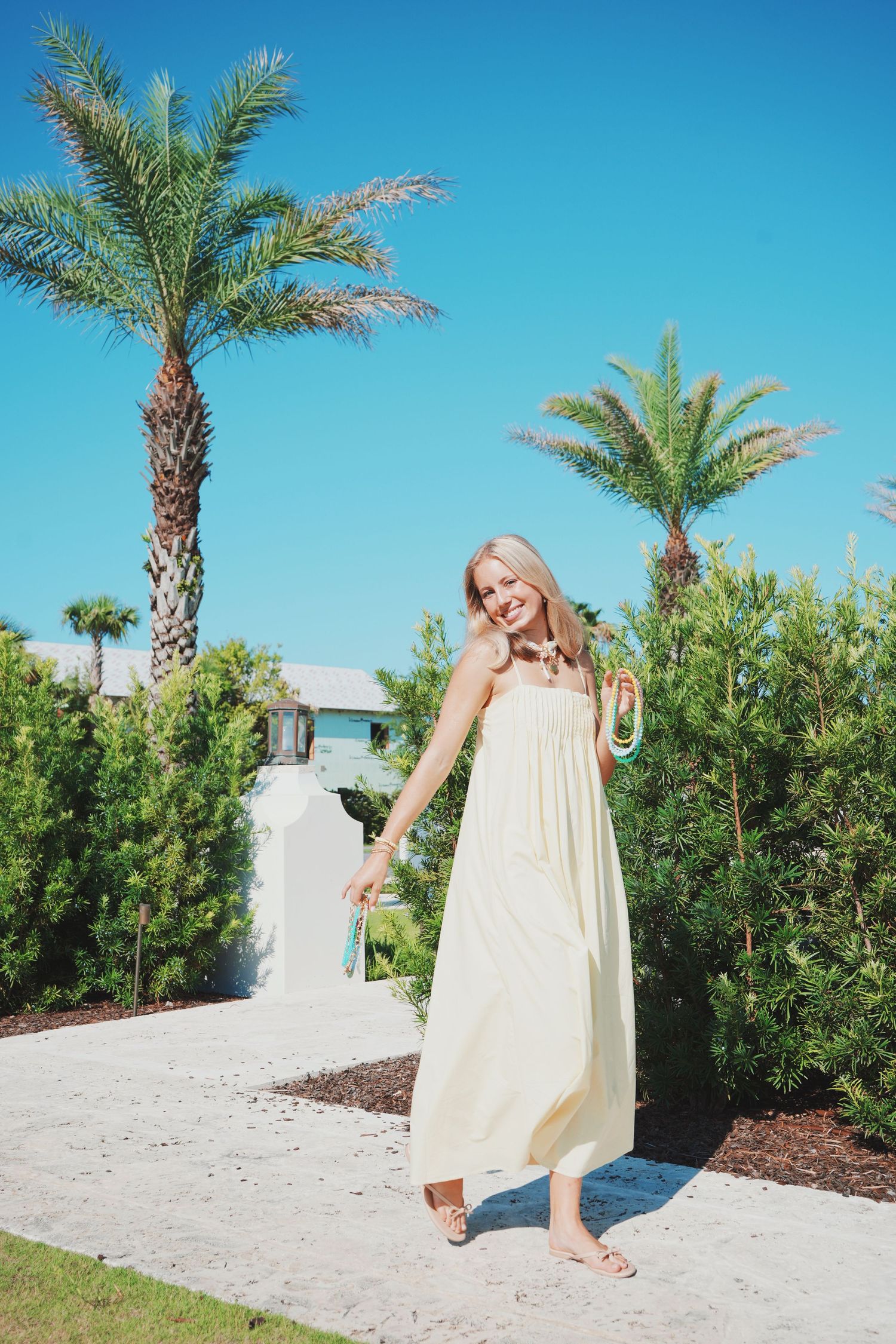 A scenic pathway lined with palm trees and greenery on a bright sunny day at a tropical resort.