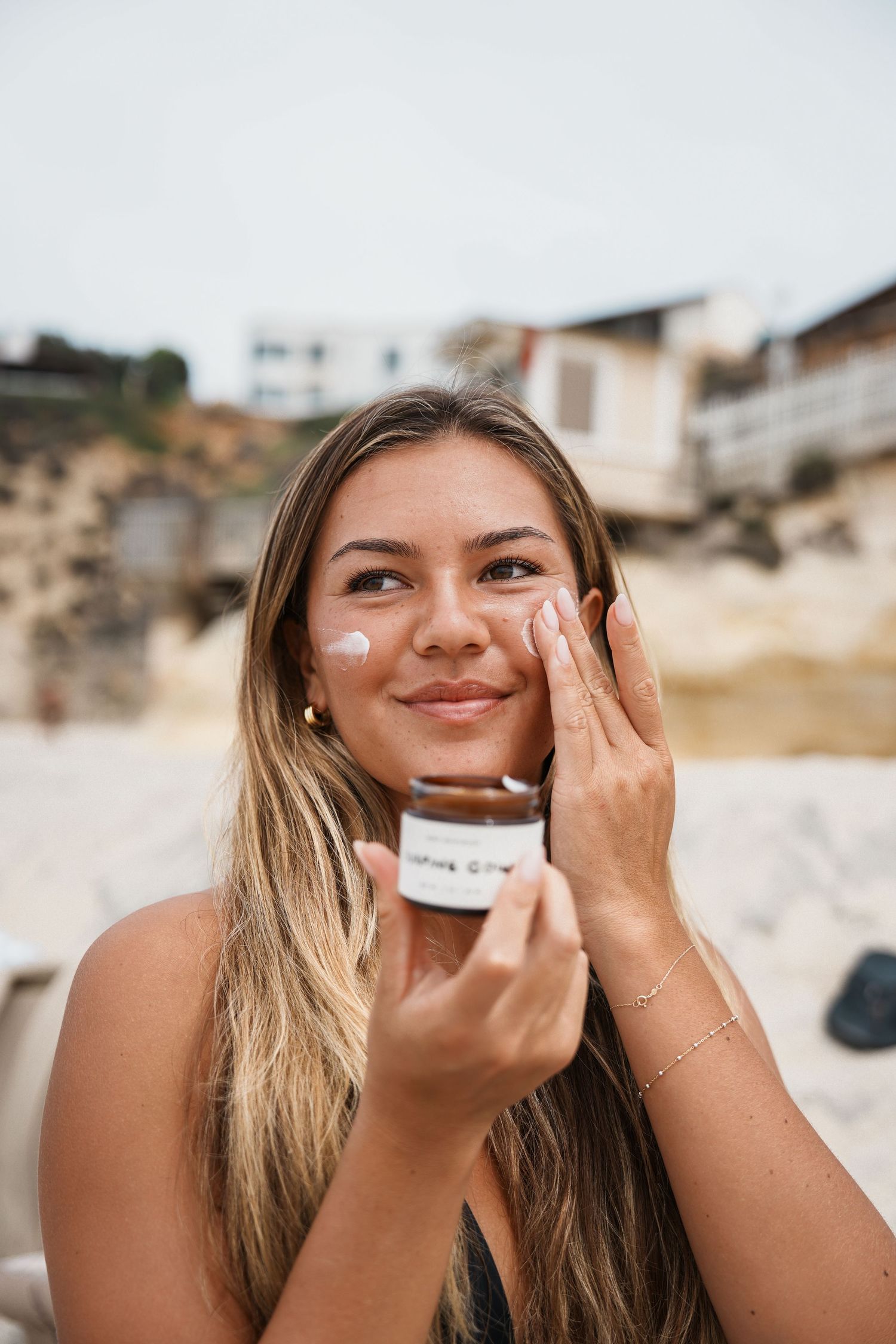 Series of images showing application of skincare product to face at the beach.