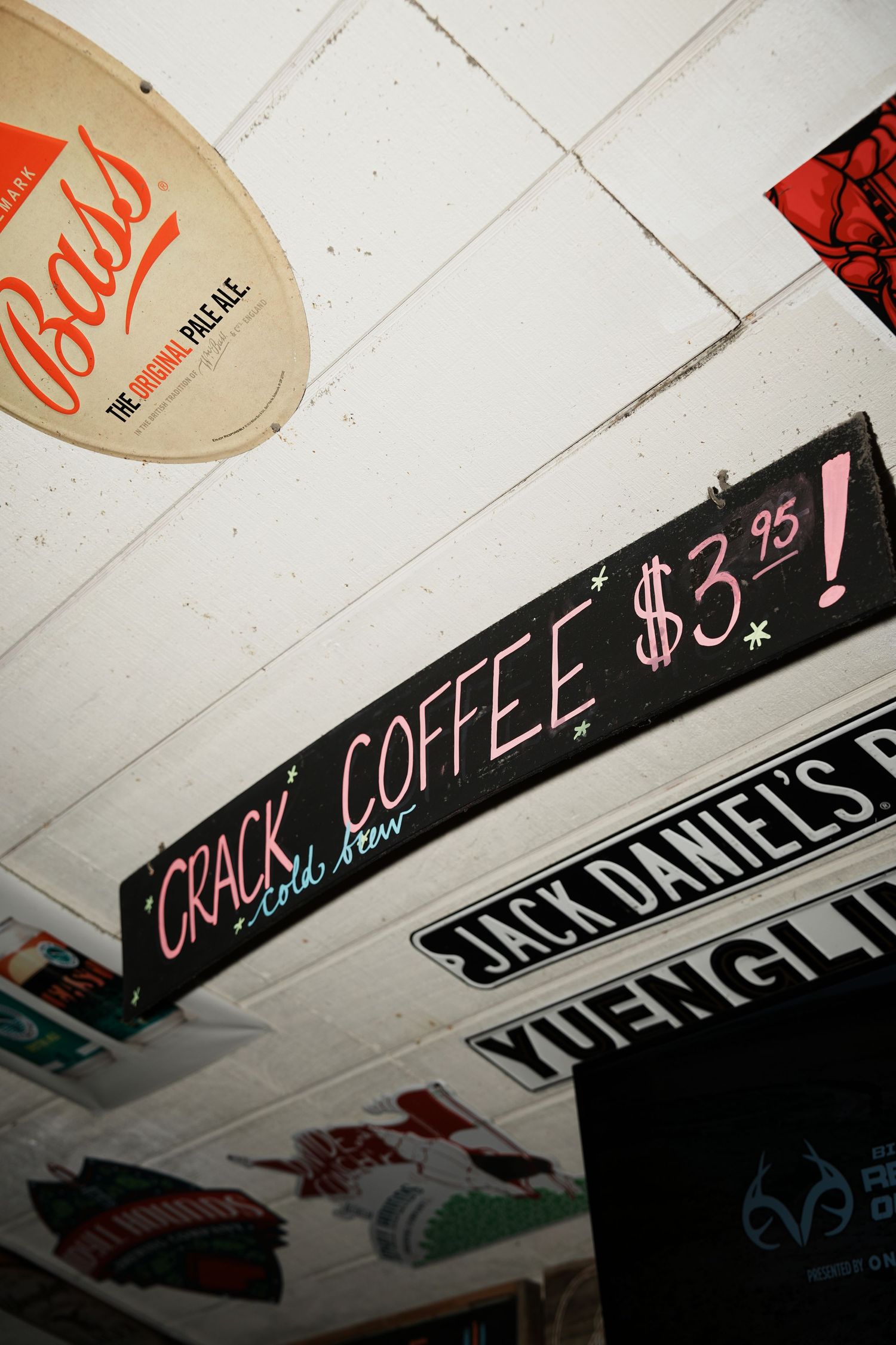 Vintage-style signage on a white ceiling advertising coffee and Jack Daniel's.
