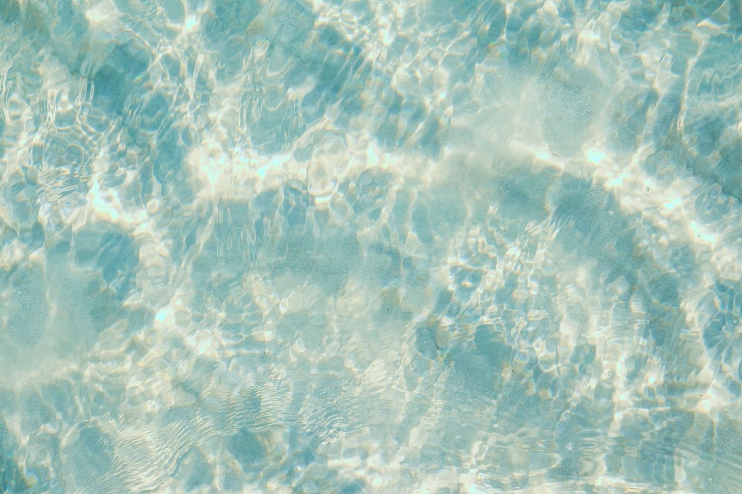 Crystal clear turquoise ocean water with sunlight creating sparkling patterns on the surface.