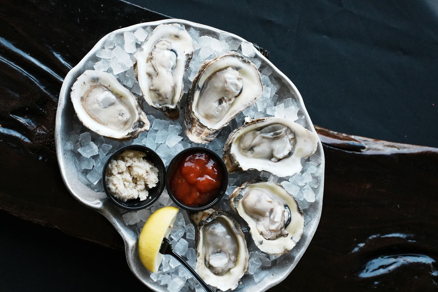 Fresh raw oysters served on ice with lemon wedges and cocktail sauce.