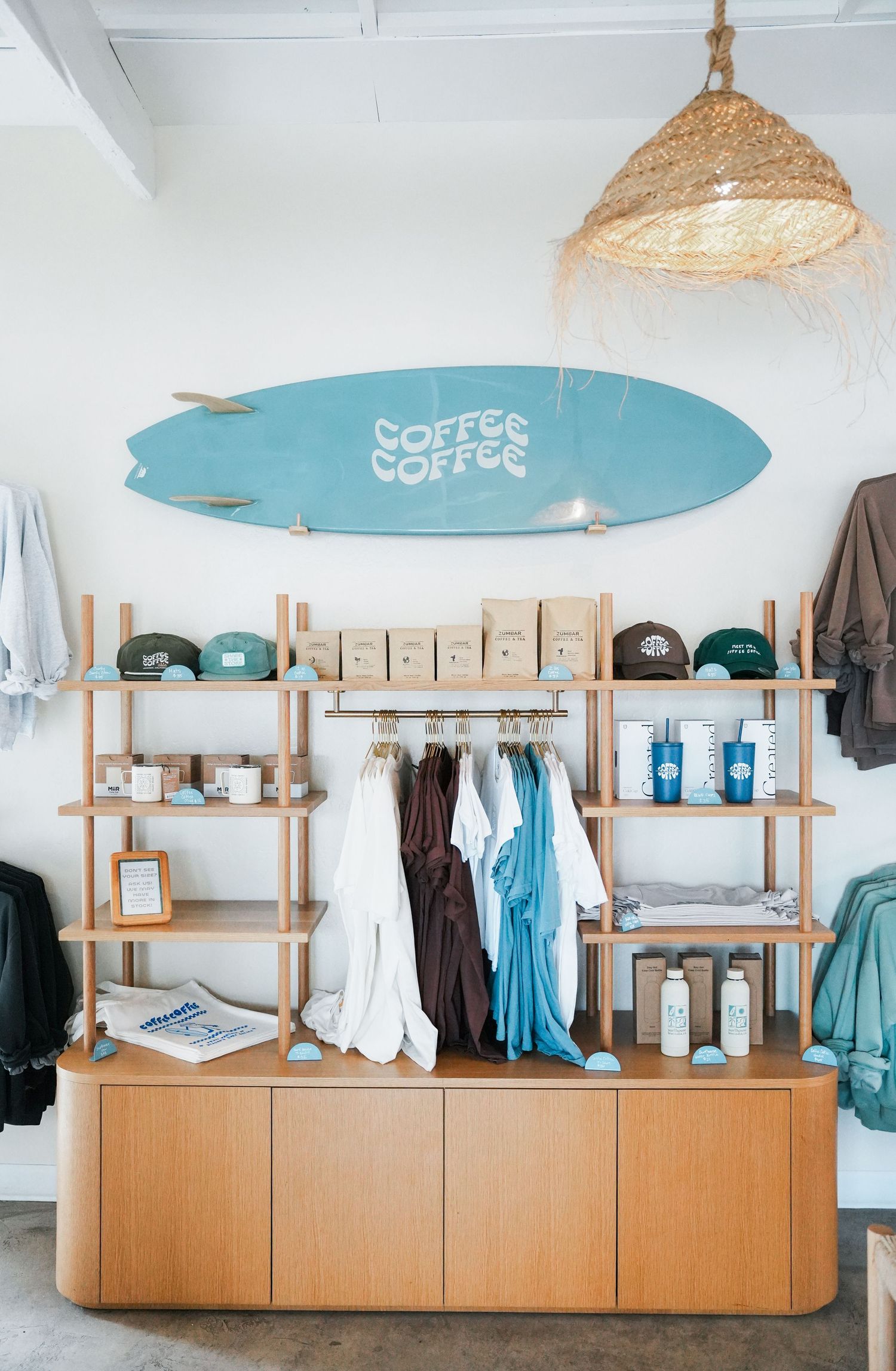 Modern surf shop interior with blue surfboard decor and wooden display shelves showcasing apparel and accessories.
