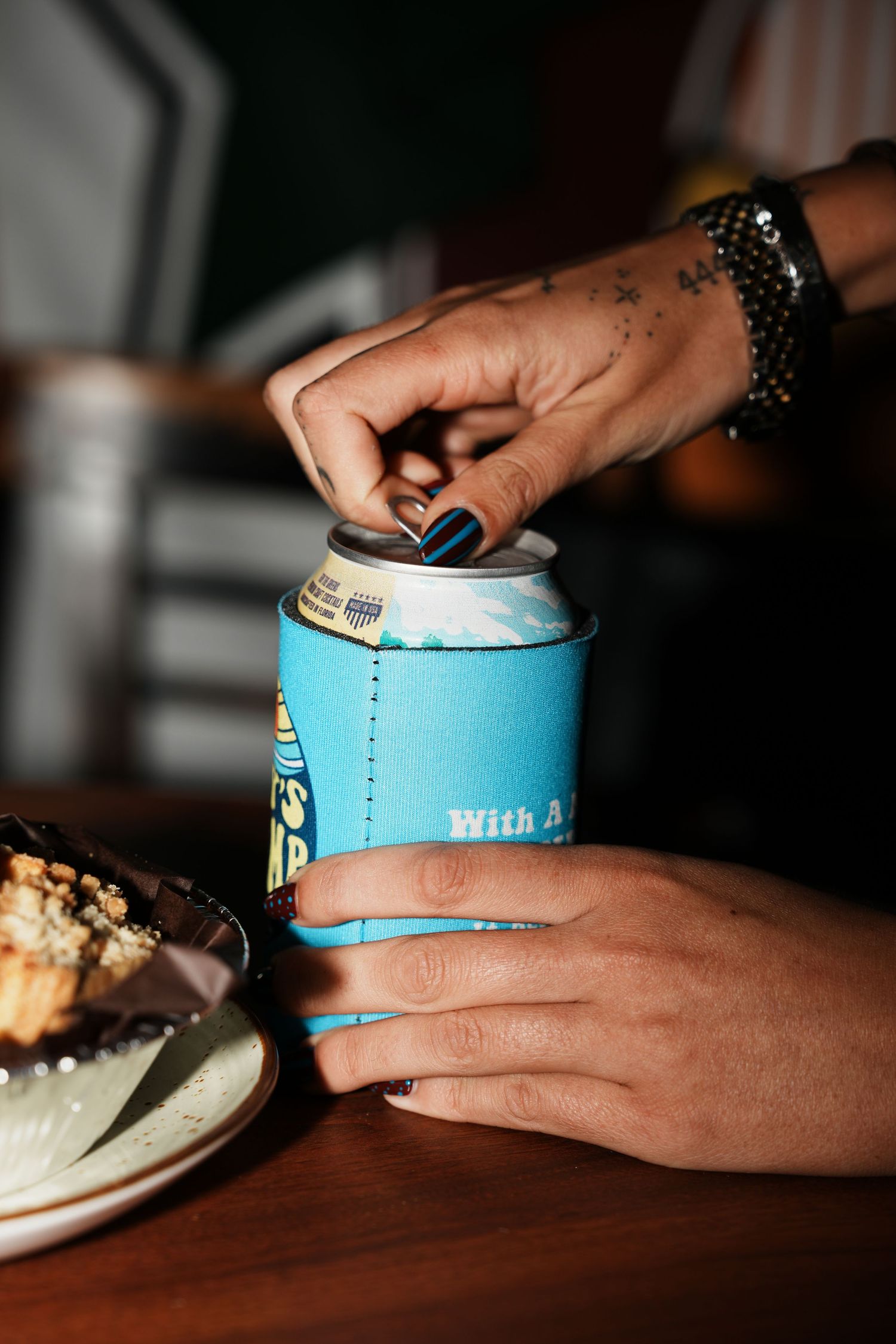 Hands with blue nail polish opening a light blue ice cream container next to a dessert plate.