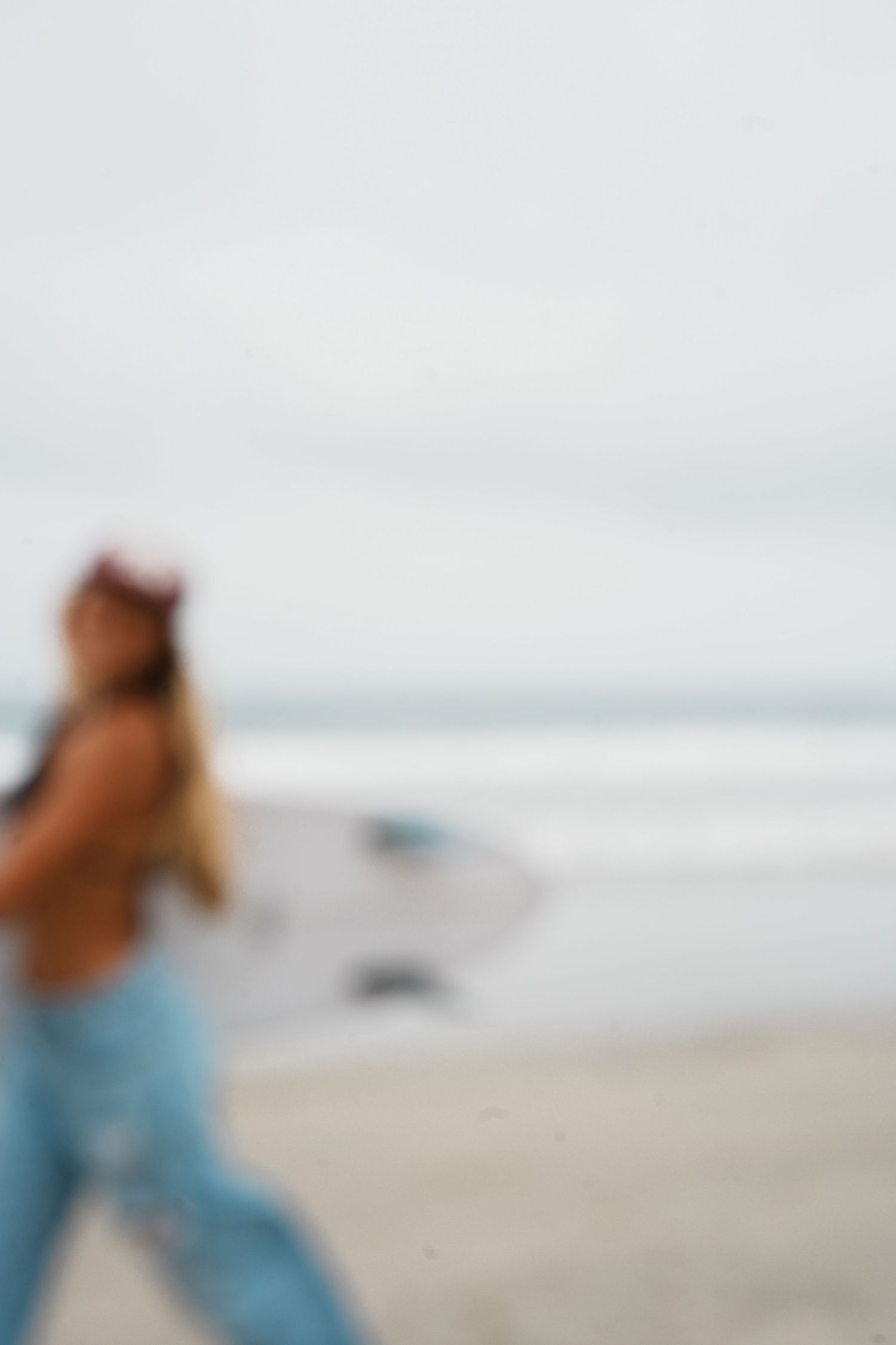 Blurred motion shot of someone walking on a sandy beach with ocean waves in the background.