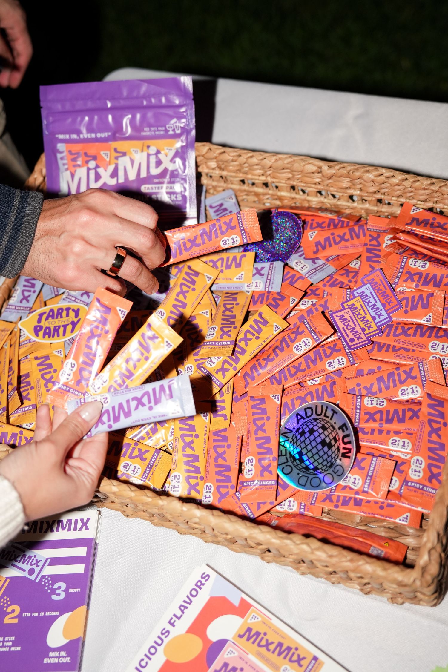 Multiple orange and purple powdered drink mix packets arranged on a wooden surface.