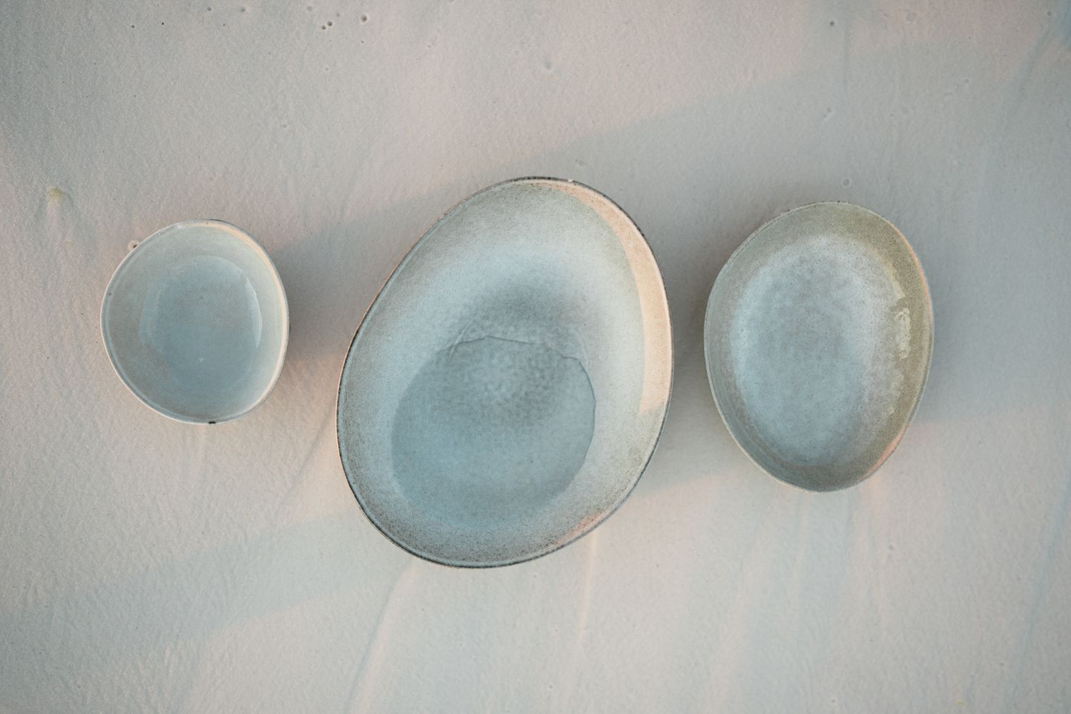Abstract close-up view of multiple pale blue ceramic bowls in various sizes arranged in a minimalist composition.