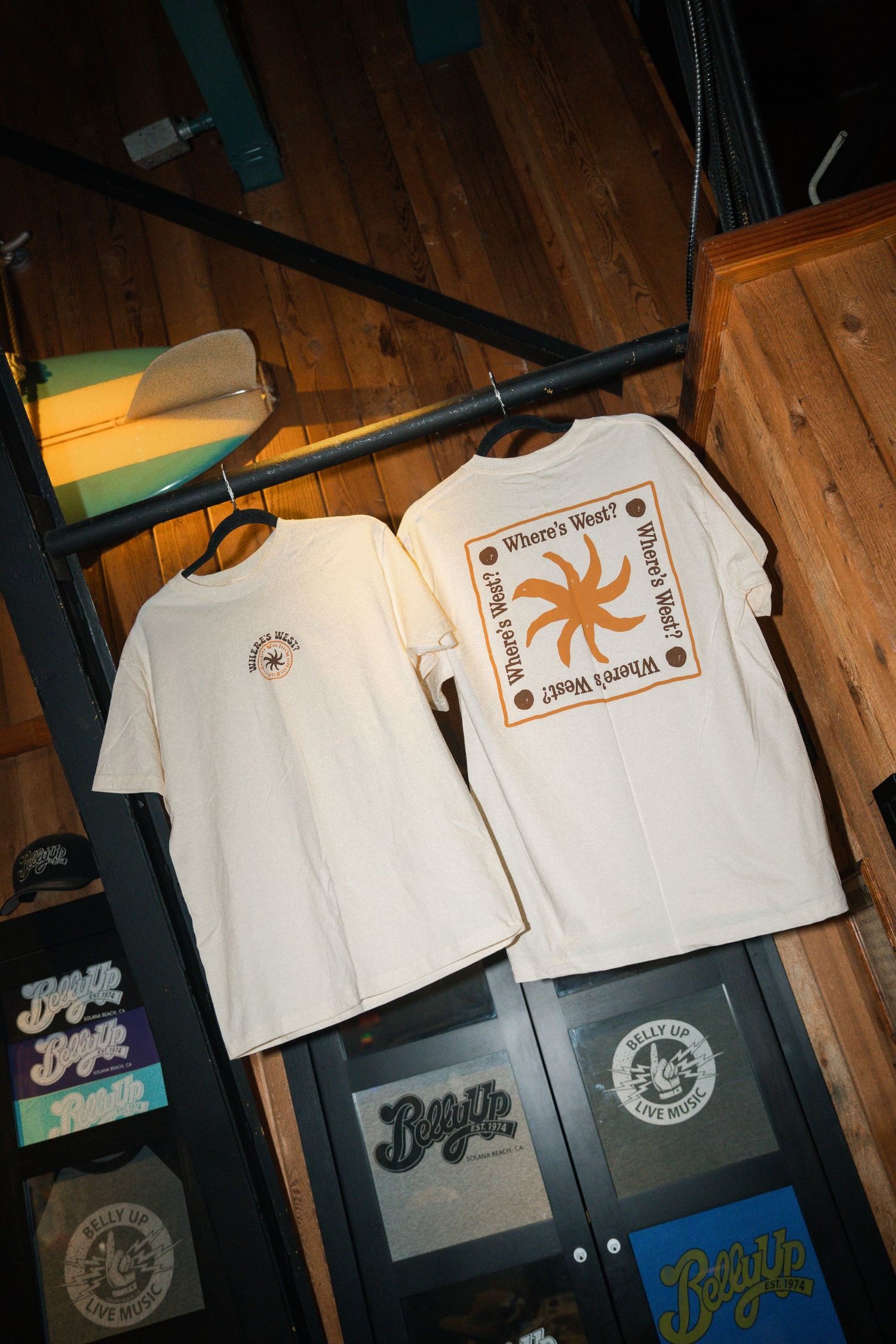 White t-shirts with custom graphics and logos displayed on wooden floor panels in progressive sequence.
