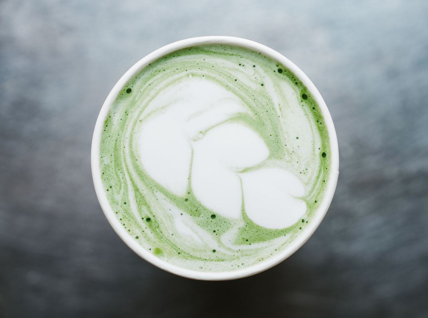 A sequence of matcha green tea lattes with white foam art shown in various stages of preparation and presentation.