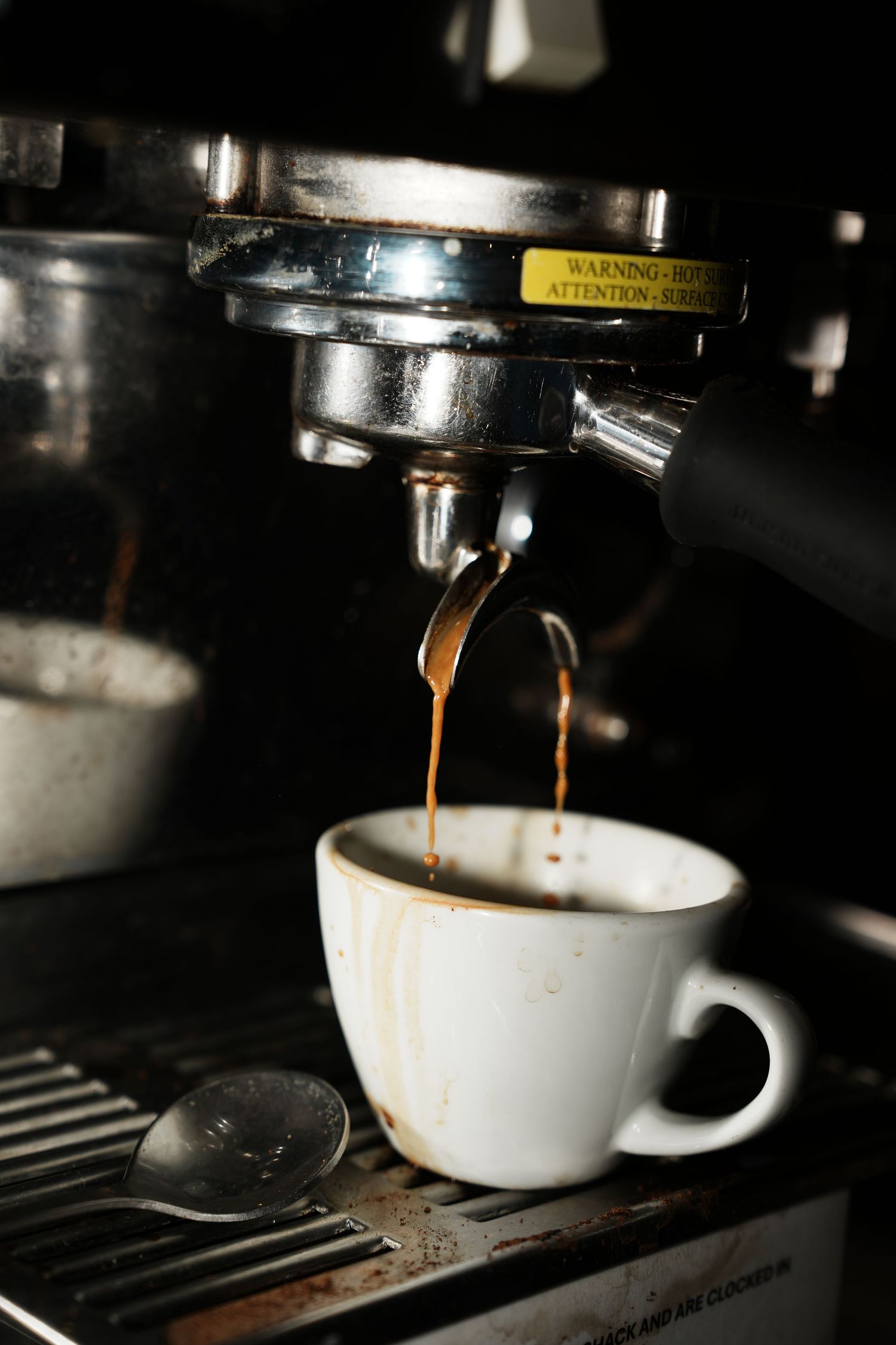 Espresso machine pouring fresh coffee into white ceramic cups on a dark background.