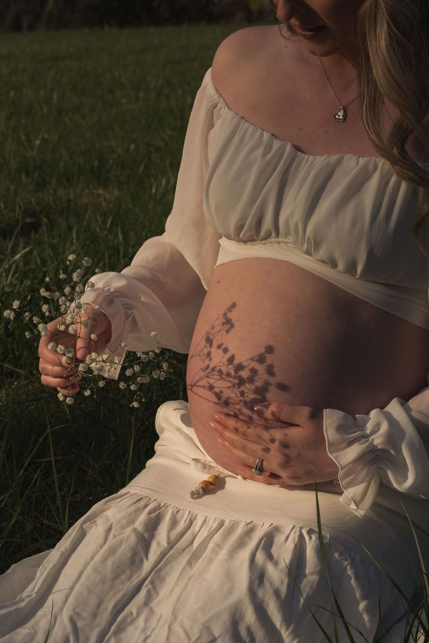 close up of shadows from flowers on pregnant woman's stomach in Silverton Oregon by Moon Street Photography