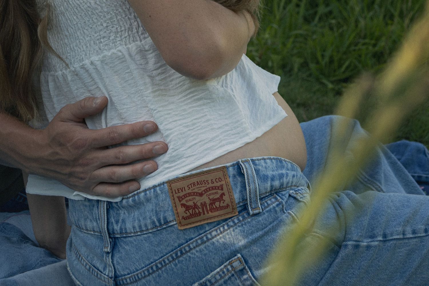Close-up detail of Levi's jeans label and white clothing in grass.
