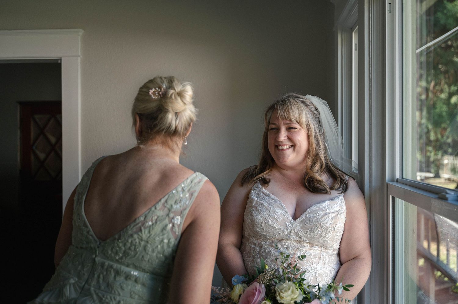 Wedding party gathered by large windows in an indoor venue.