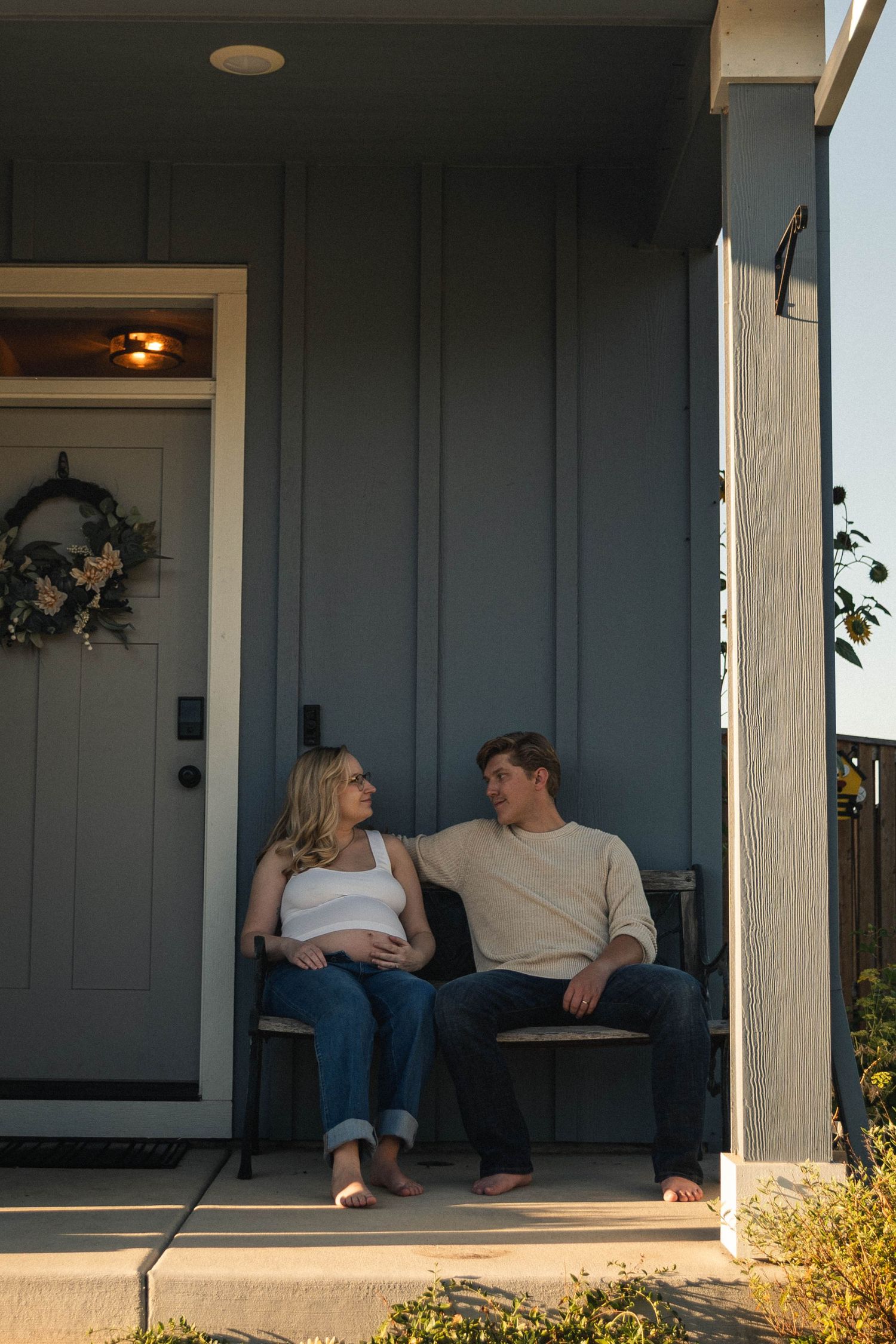 Pregnant woman and her husband sitting in the sun outside of their home in Oregon.