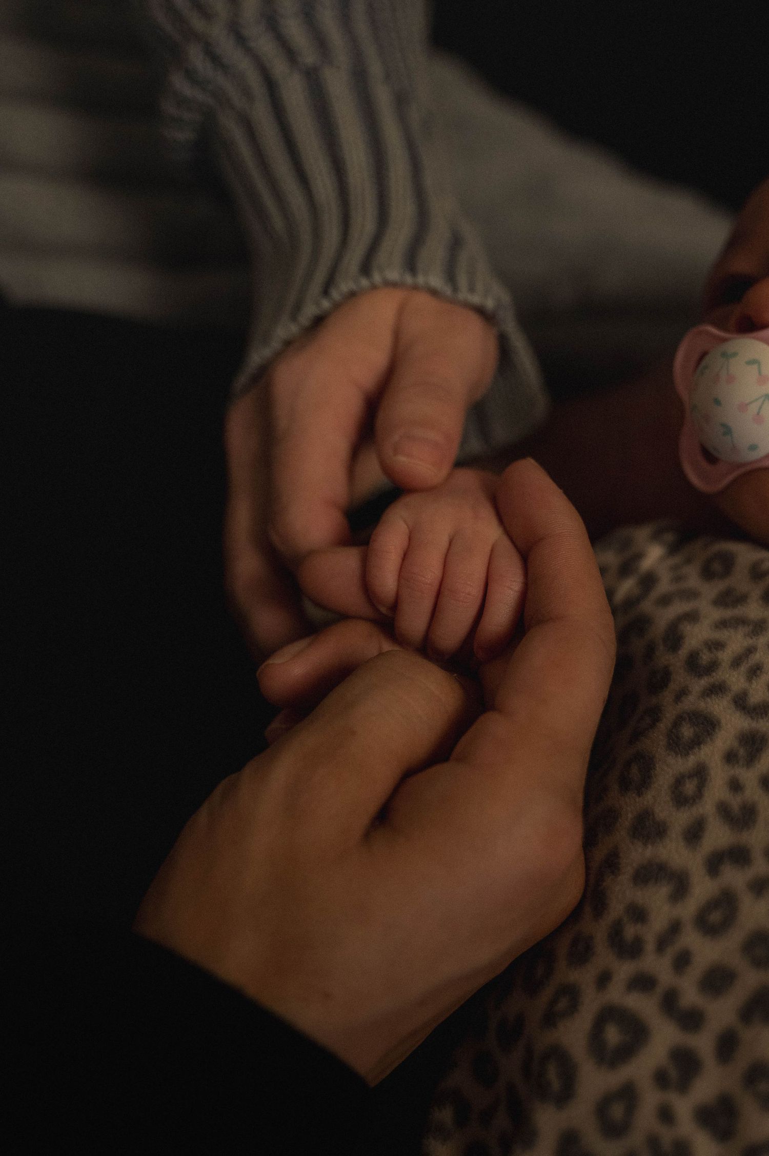Close up of mother, father, and baby's hands together.