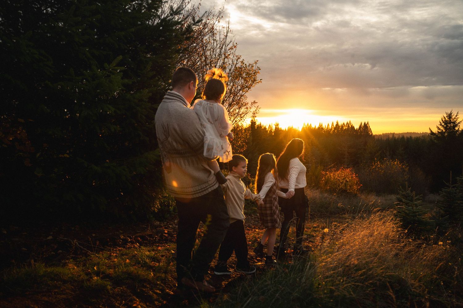 Group walking on hillside path silhouetted against vibrant sunset sky.