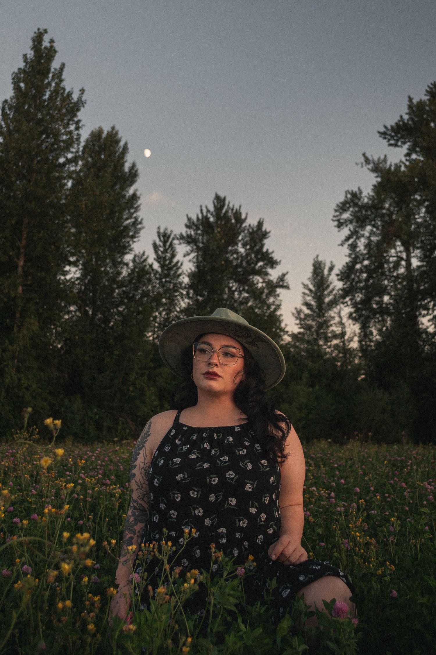woman sitting in a clover field under a bright, summer evening moon at Willamettte Mission State Park