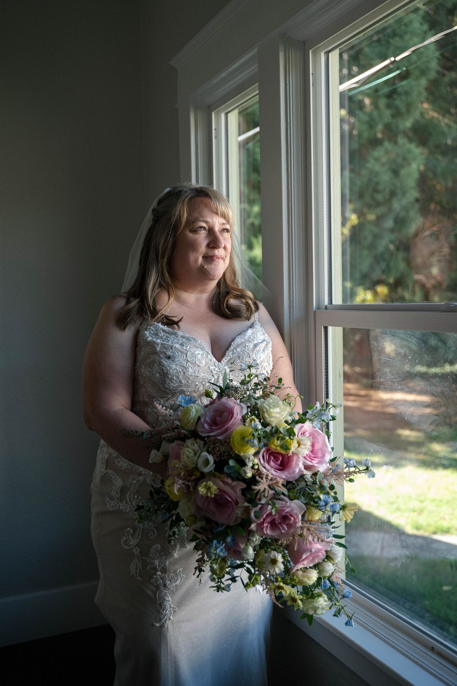 Beautiful bridal bouquet with colorful flowers and greenery by a sunlit window.