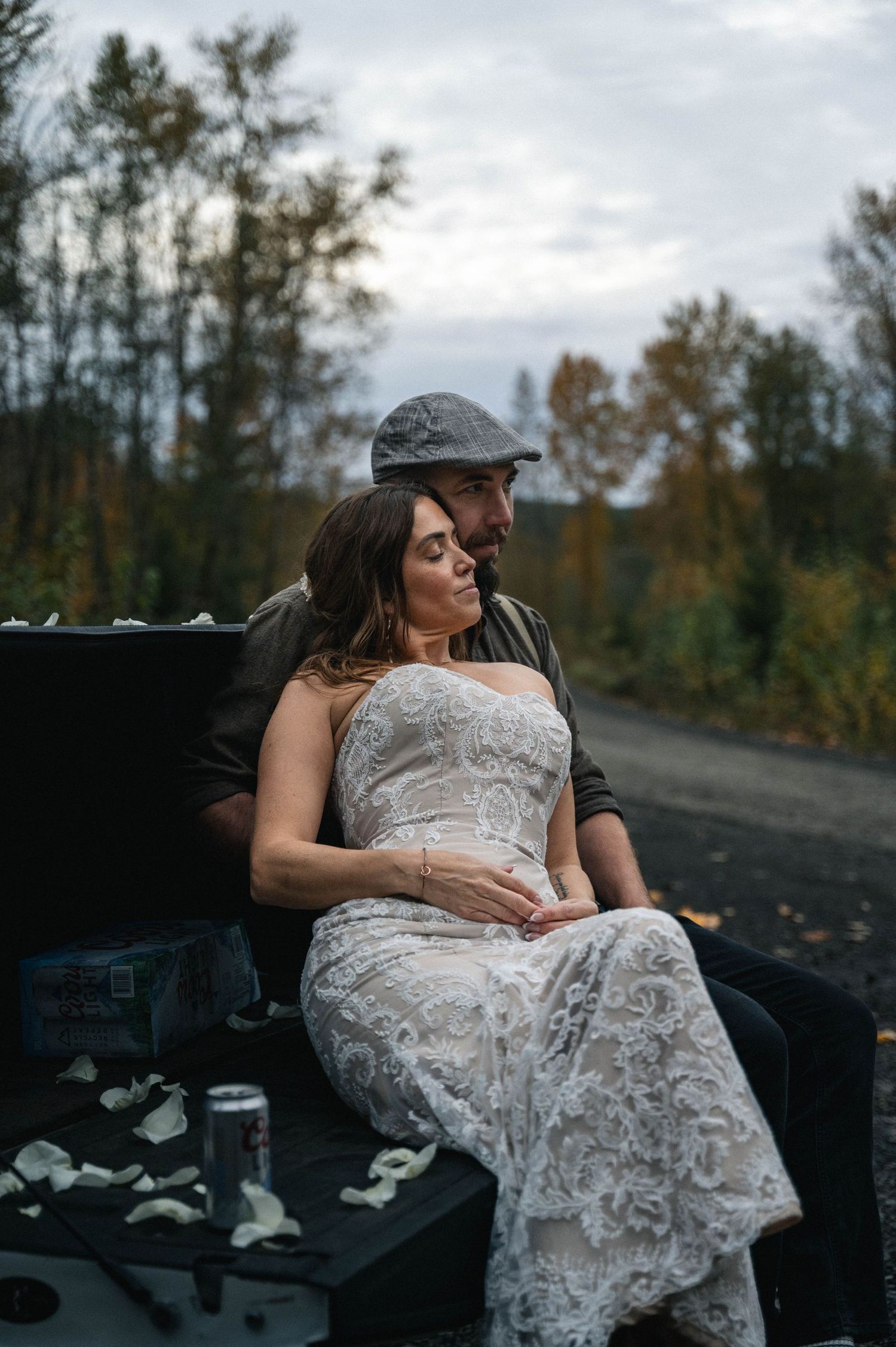 A couple in formal attire share an intimate moment on dark rocks during an outdoor photo session at dusk.