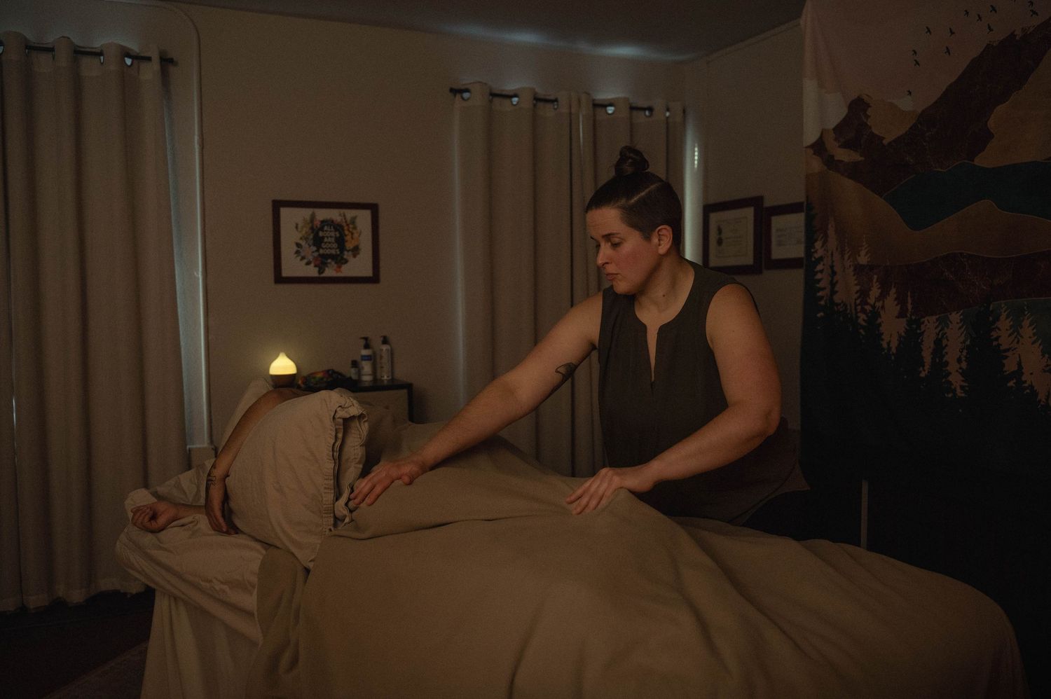 Person receiving a relaxing massage therapy treatment on a table in a dimly lit spa room.
